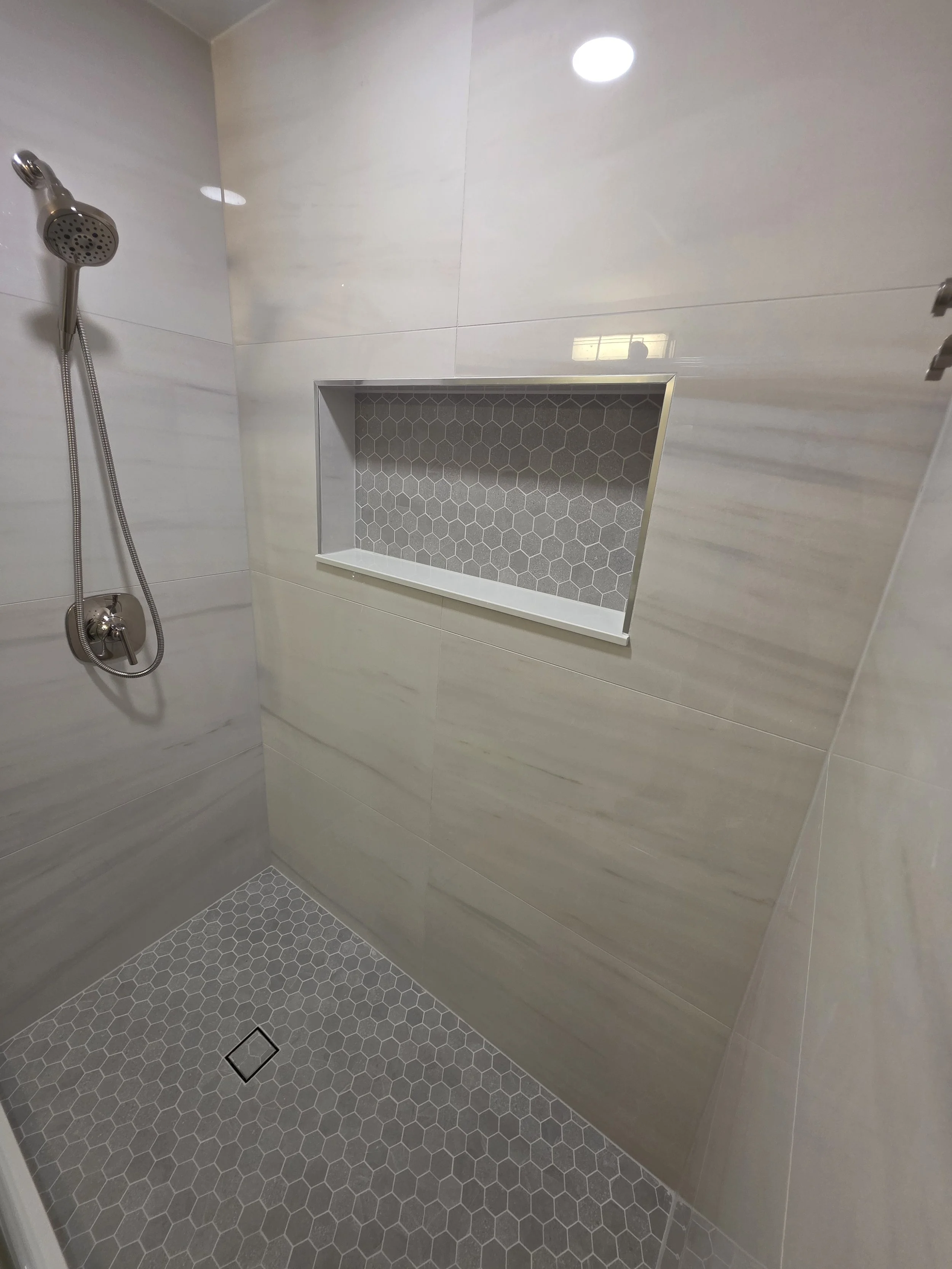 Shower fixture and mosaic-lined recessed niche.
