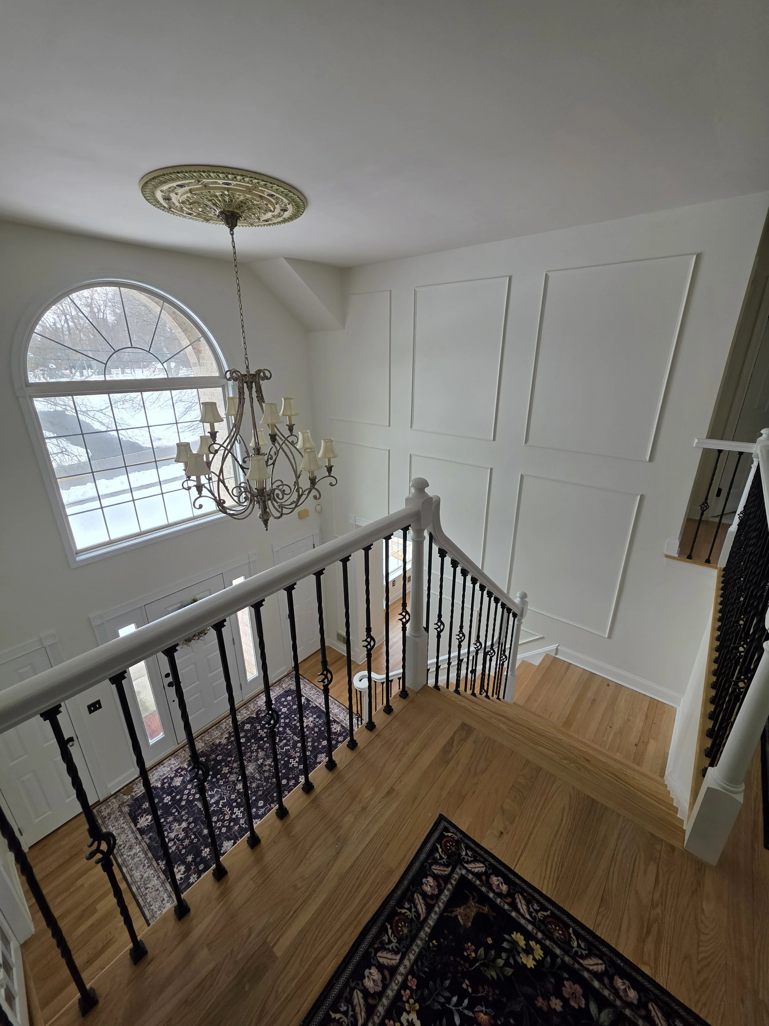 View over the remodeled landing toward the chandelier and arched window.