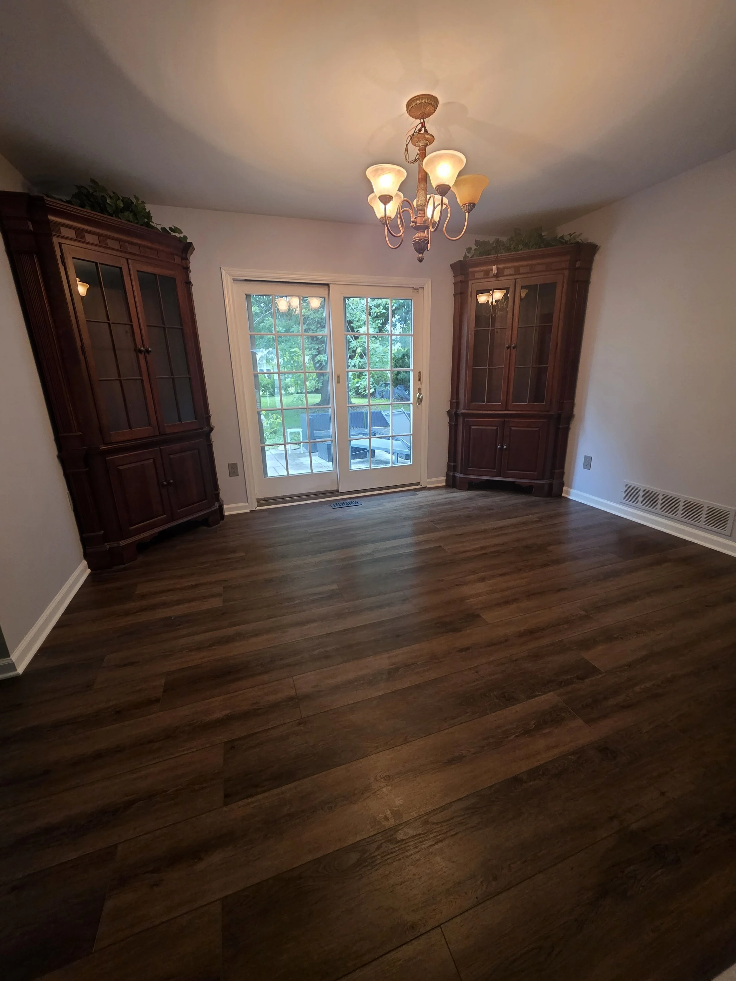Angled view across the finished dining-room floor toward the glass doors.