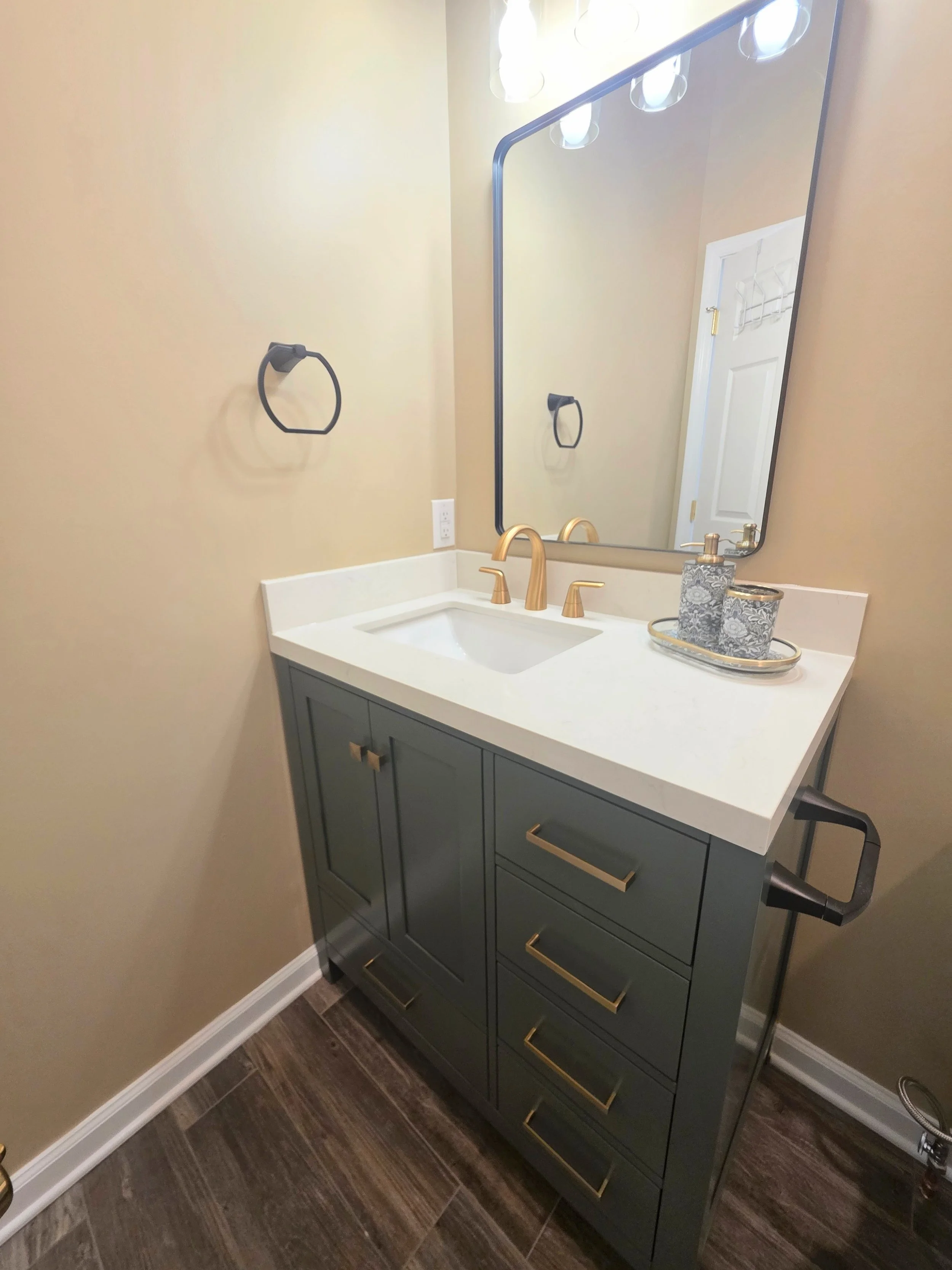 Angled view of the green vanity, white countertop and wood-look floor.