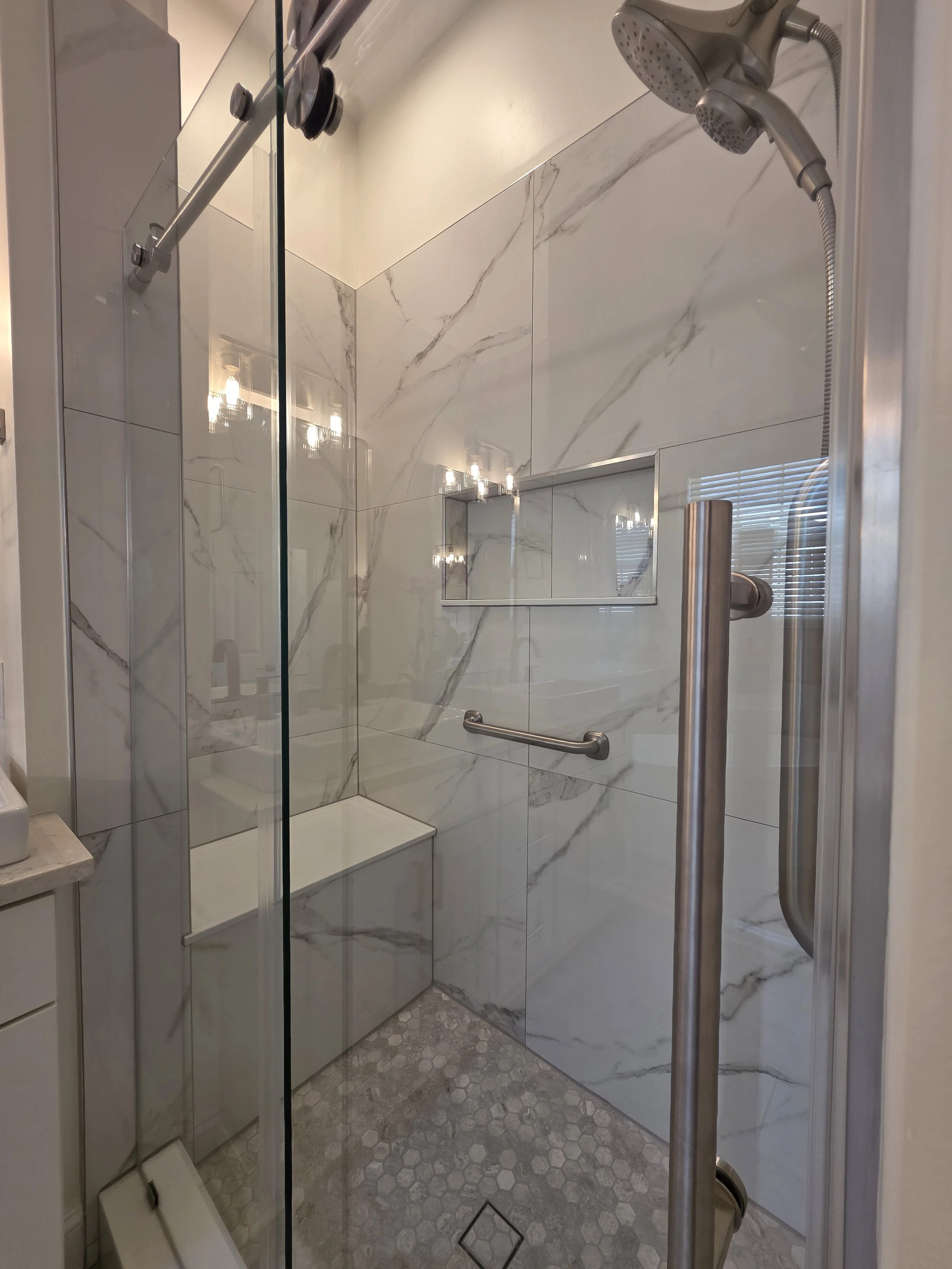 Glass shower door with chrome fixtures.