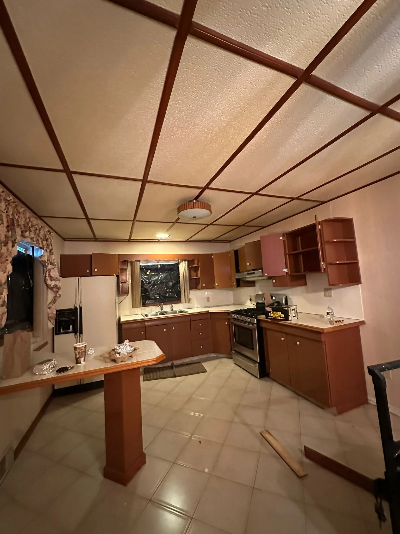 Before renovation: Samuel’s original kitchen with older cabinets, tiled floor and paneled ceiling.