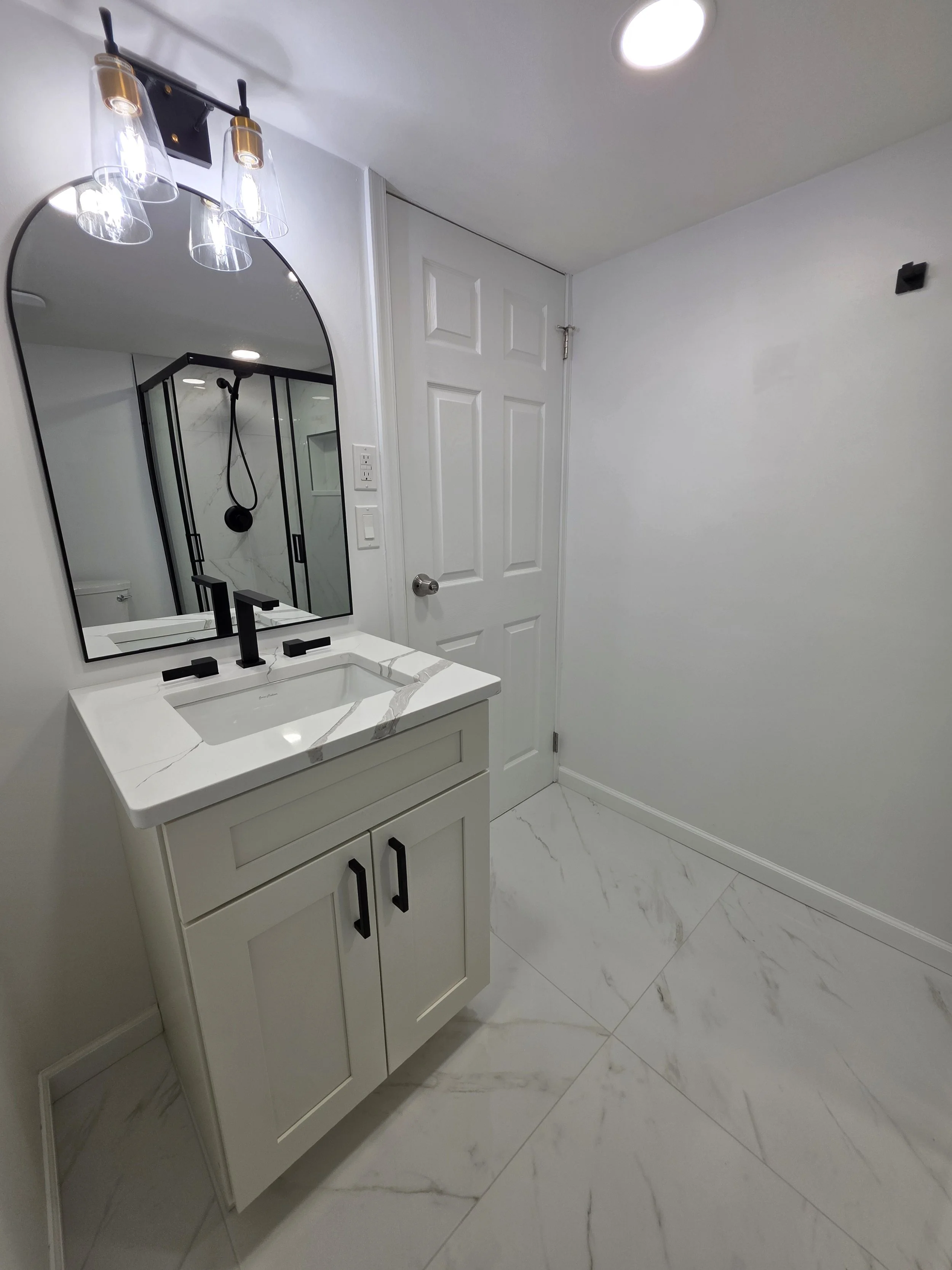 View of the white vanity and marble-look floor tile near the basement bathroom doorway.