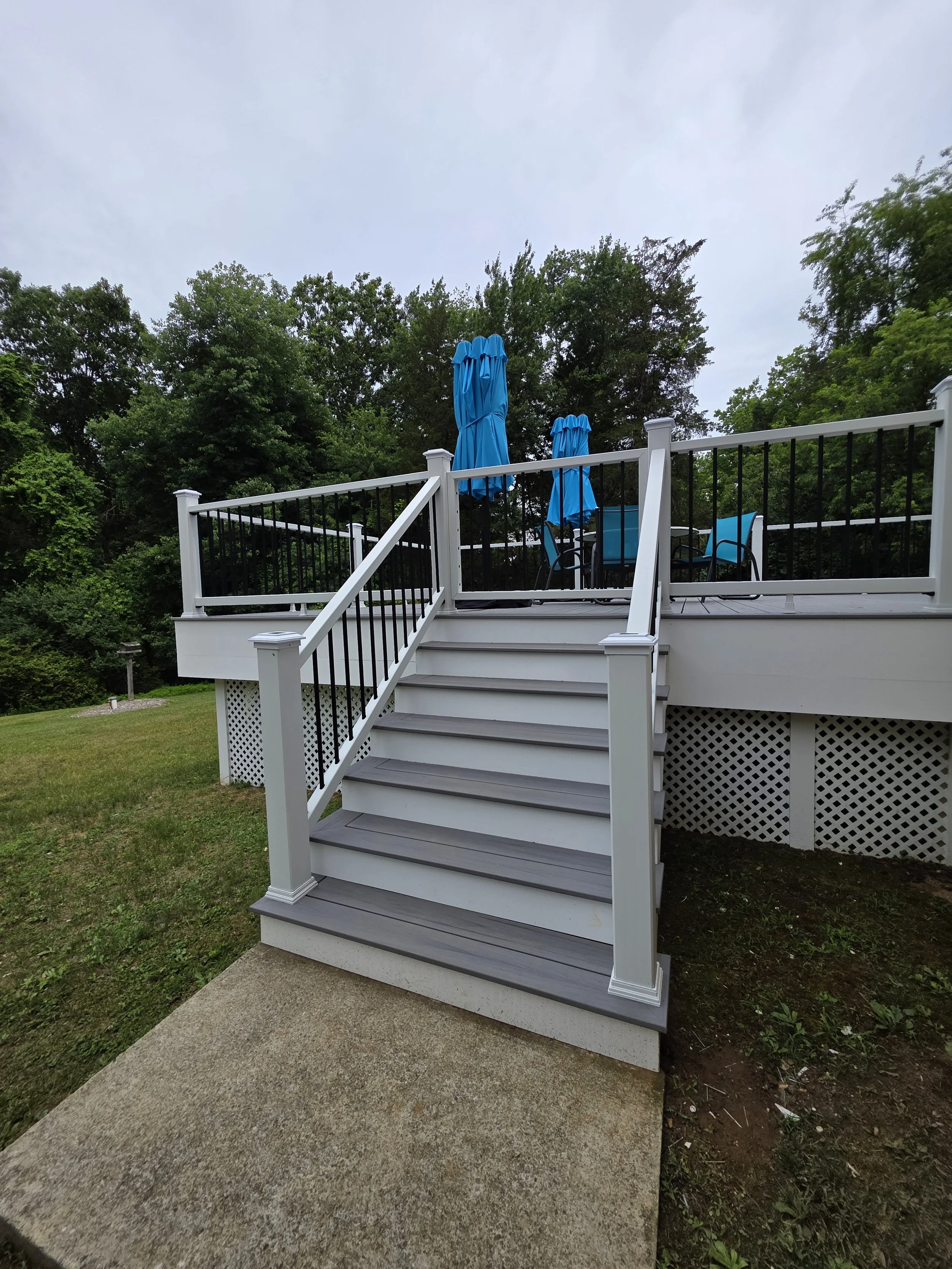 Front view of the replacement deck stairs with gray treads, white posts, and black balusters.