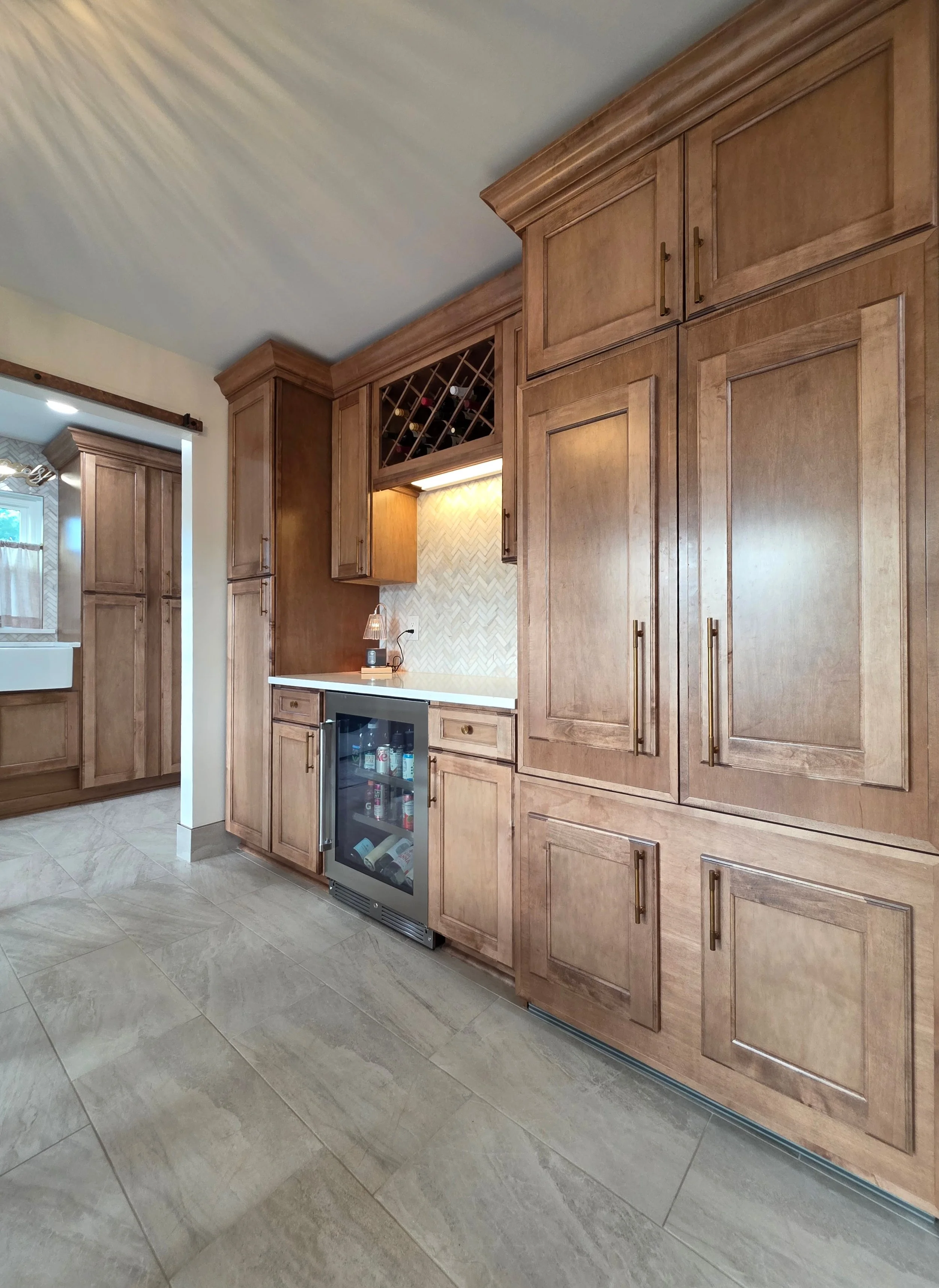 Close view of the beverage refrigerator and pantry cabinetry with matching crown trim.