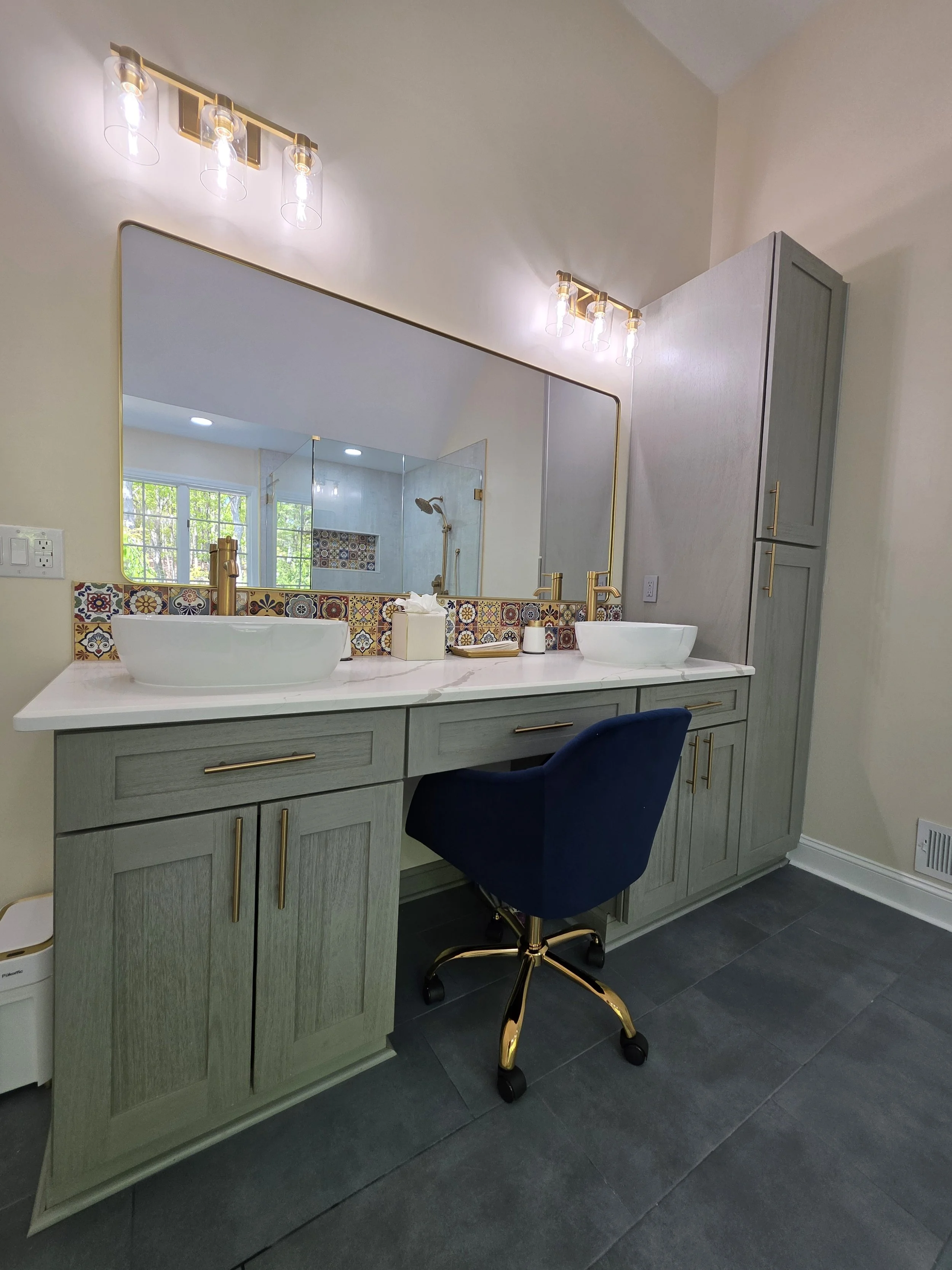 Wide vanity view with two vessel sinks, a makeup seat and tall matching storage cabinet.