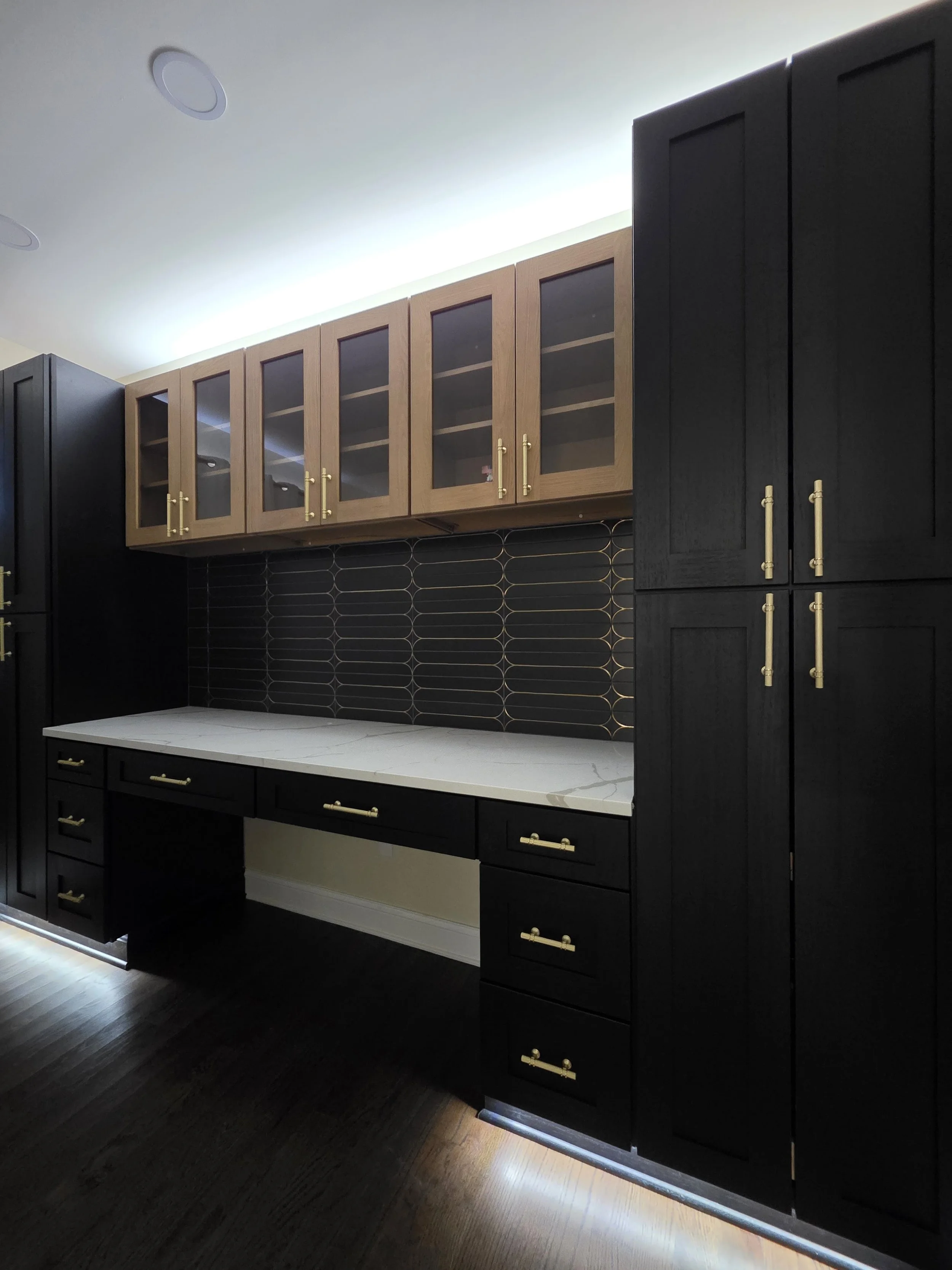 Home office cabinetry with light desktop and dark backsplash.