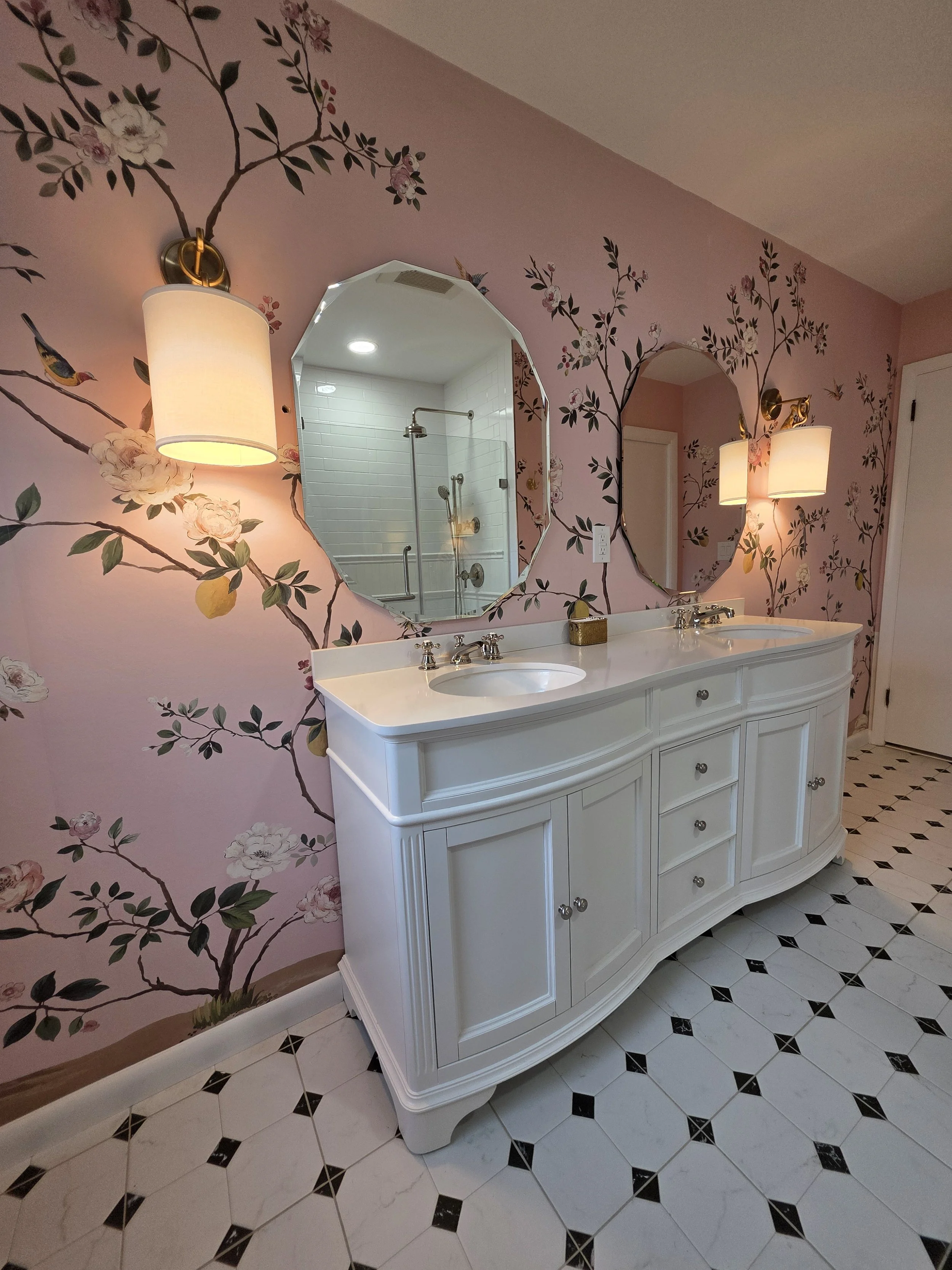 Double vanity with arched mirrors and warm wall lights.