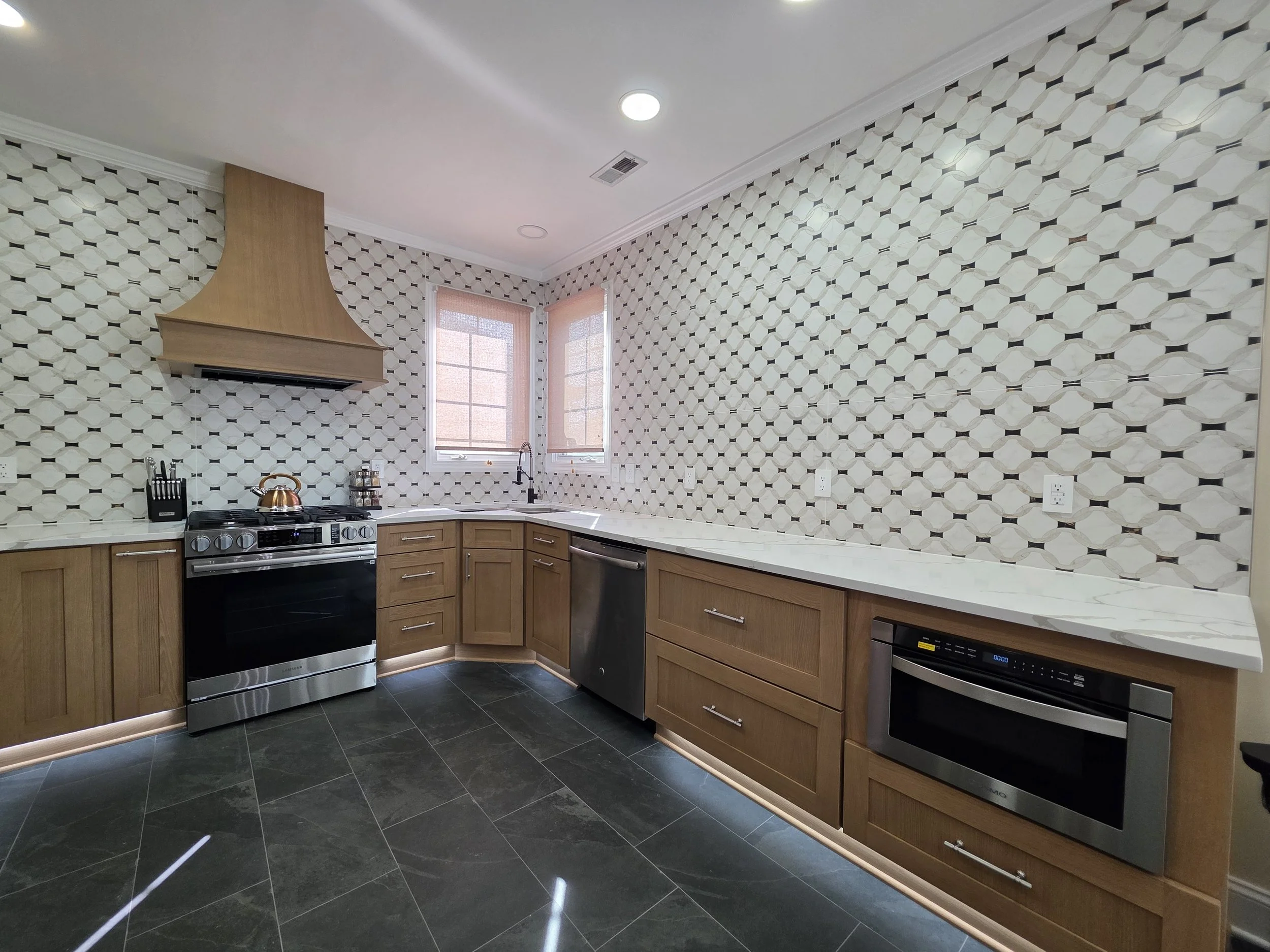 Augusta’s completed kitchen with wood cabinets, patterned tile and matching range hood.