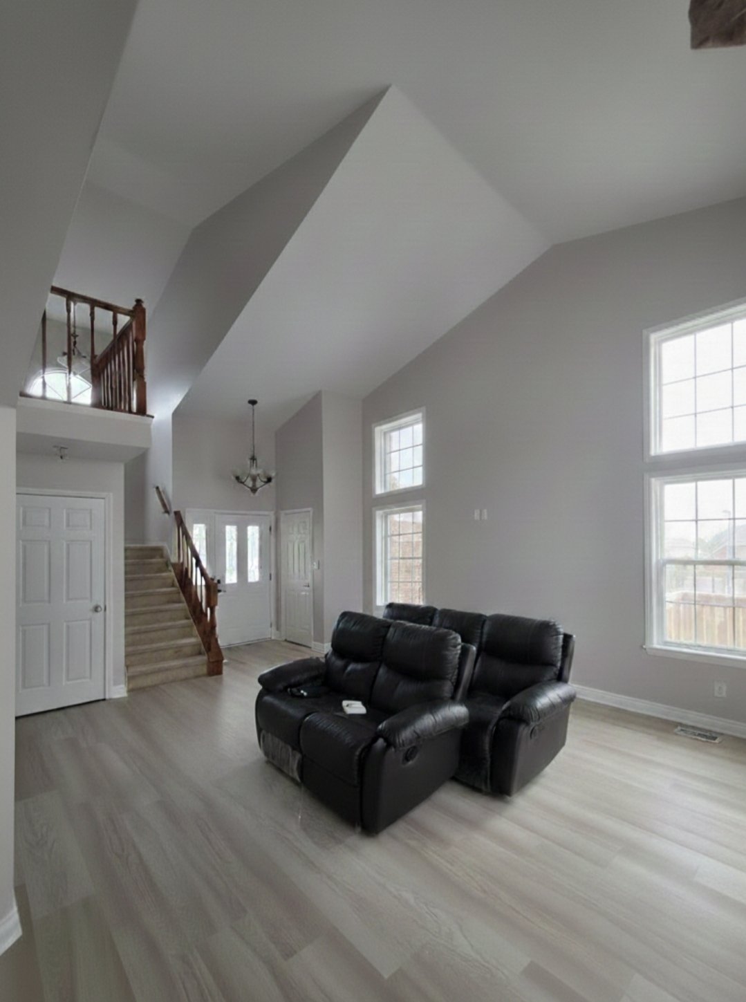 Sally and Jason’s refreshed living room with light wood-look vinyl flooring, pale walls and tall windows.