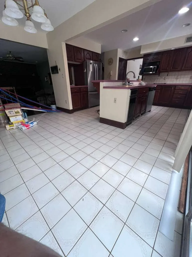 Before renovation: the original kitchen and dining area with older cabinetry and square floor tile.