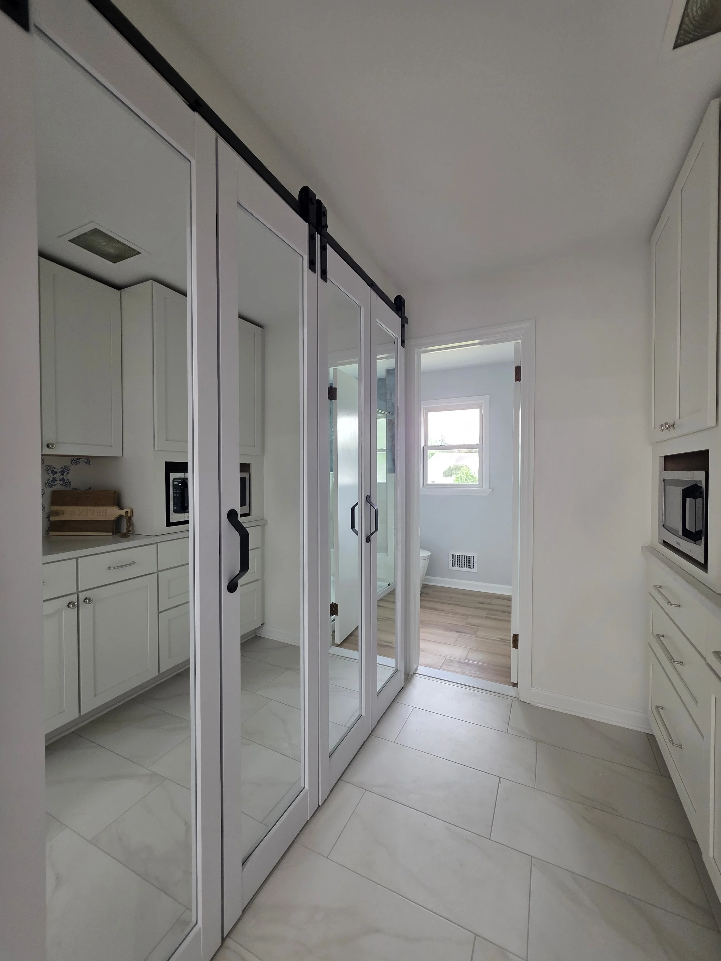Mirrored sliding laundry closet doors beside pantry cabinetry.