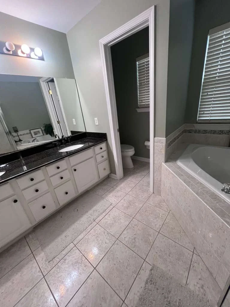 Before renovation: the original double vanity, tiled floor and enclosed bathtub area.