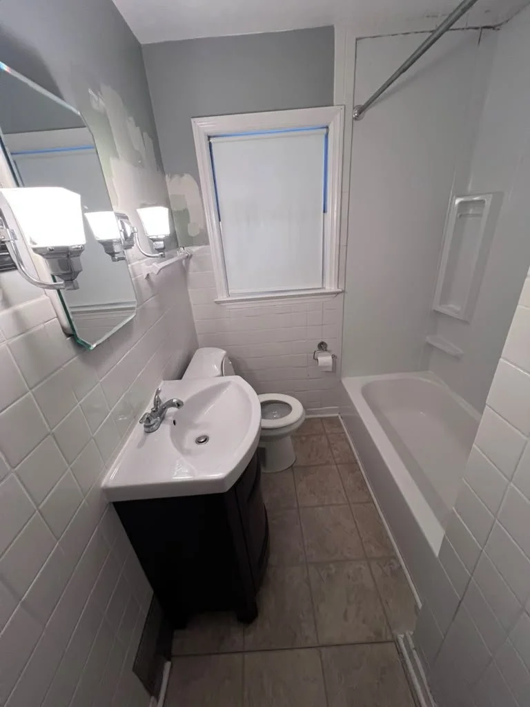 Hallway bathroom before renovation with white wall tile.