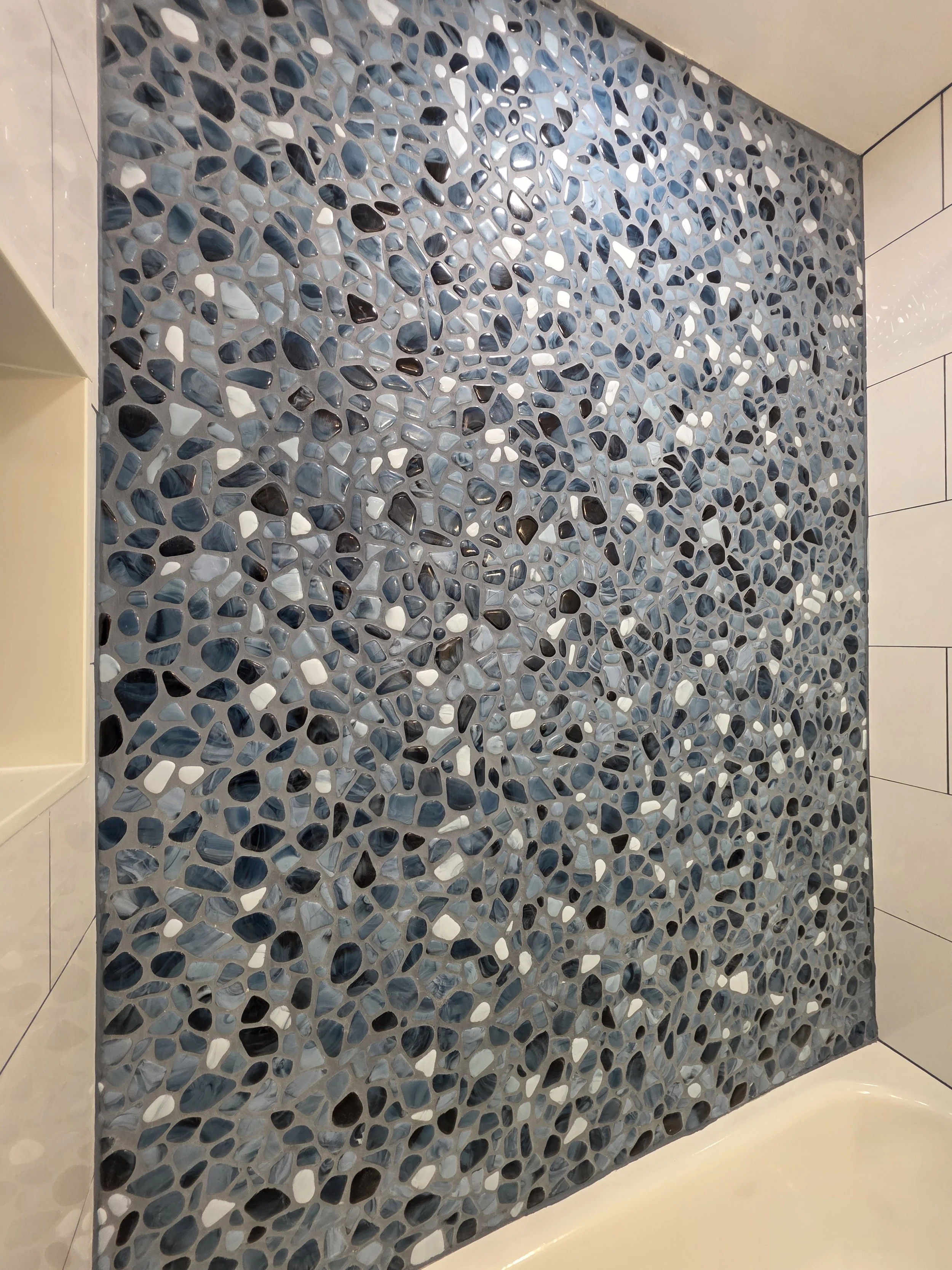 Another view of the river rock accent tile meeting the white tub and adjoining wall tile.