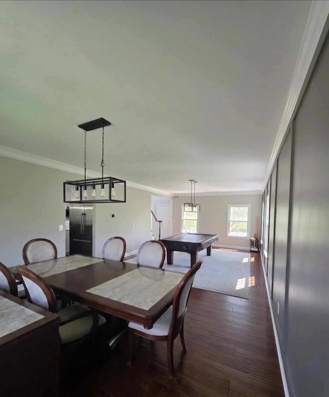 View from the dining table toward the game room, showing updated light fixtures and the accent wall.