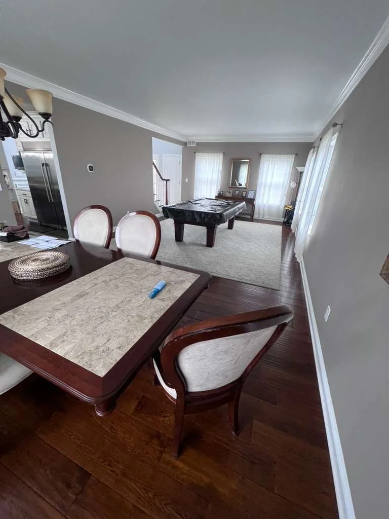 Before renovation: view across the dining table toward the pool table and unpaneled walls.