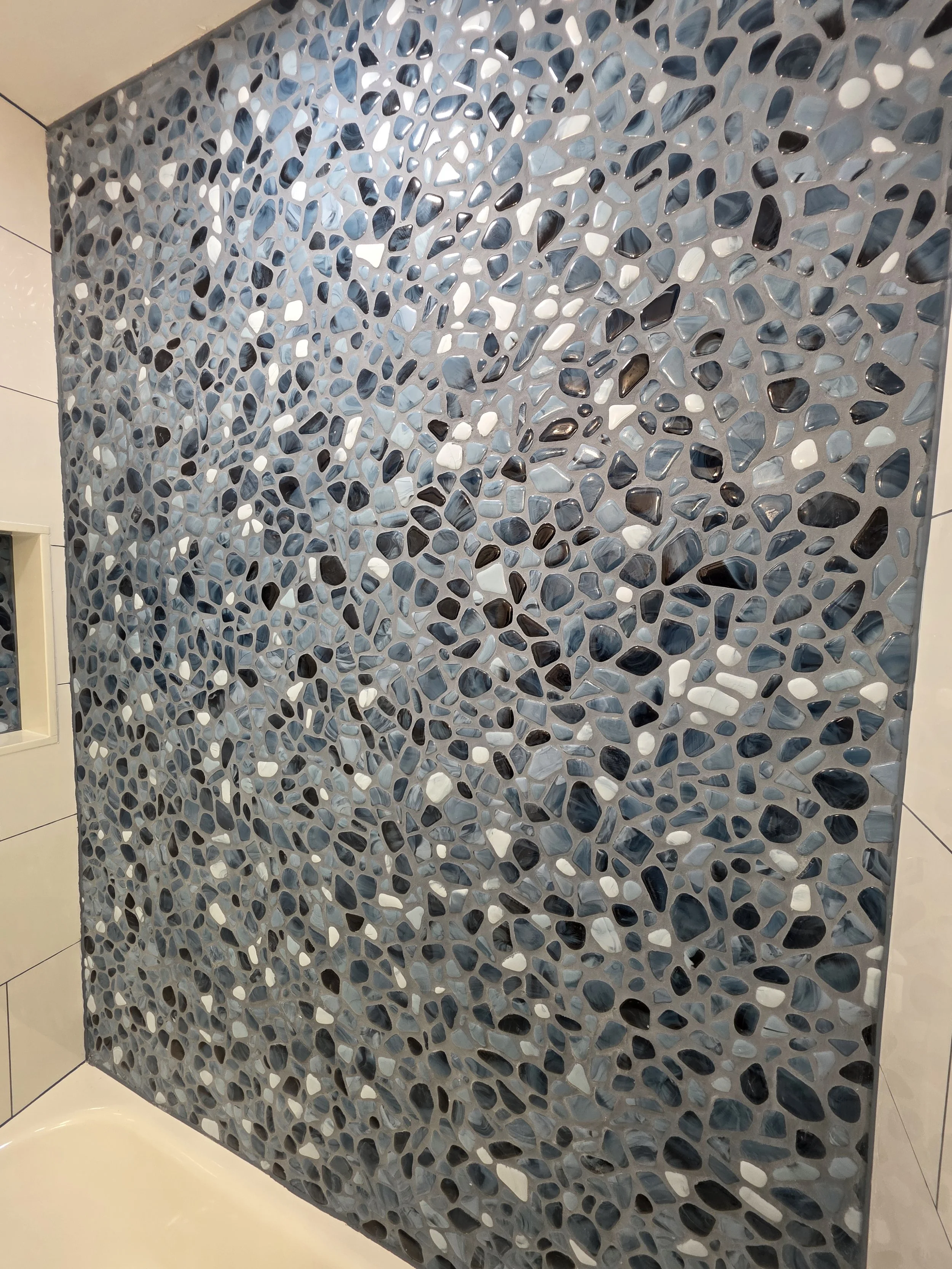 Detailed view of the blue and gray river rock tile pattern across the tub accent wall.