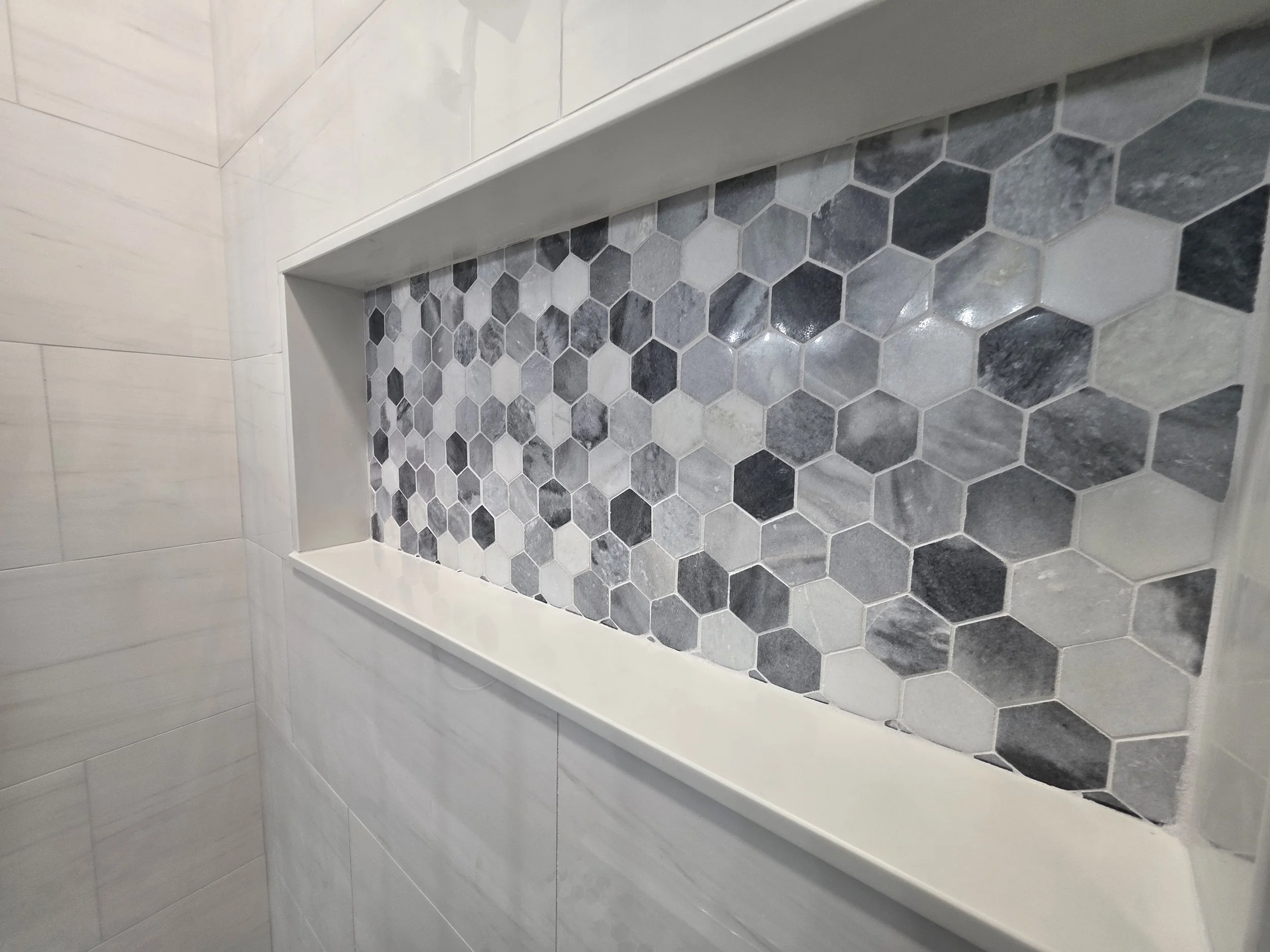 Close-up of hexagonal mosaic shower niche.