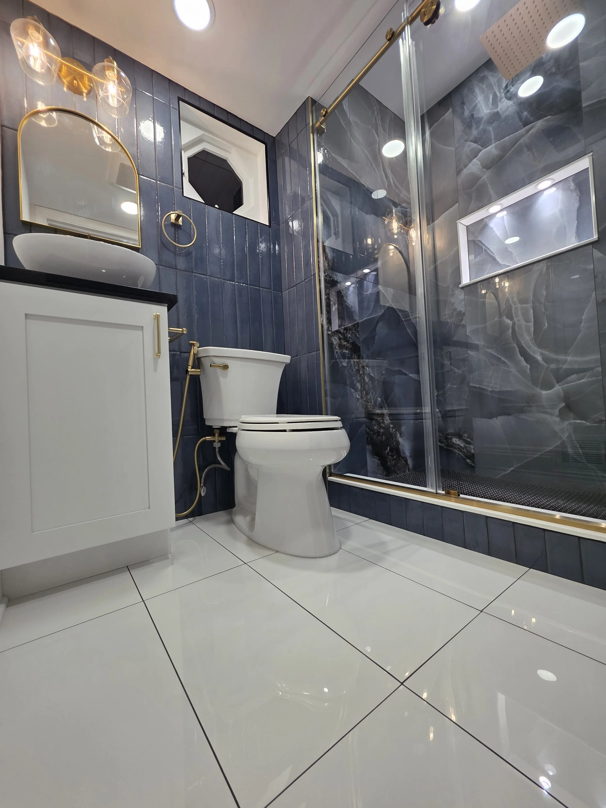 Low view of the white vanity, toilet and glass shower enclosure above large white floor tiles.