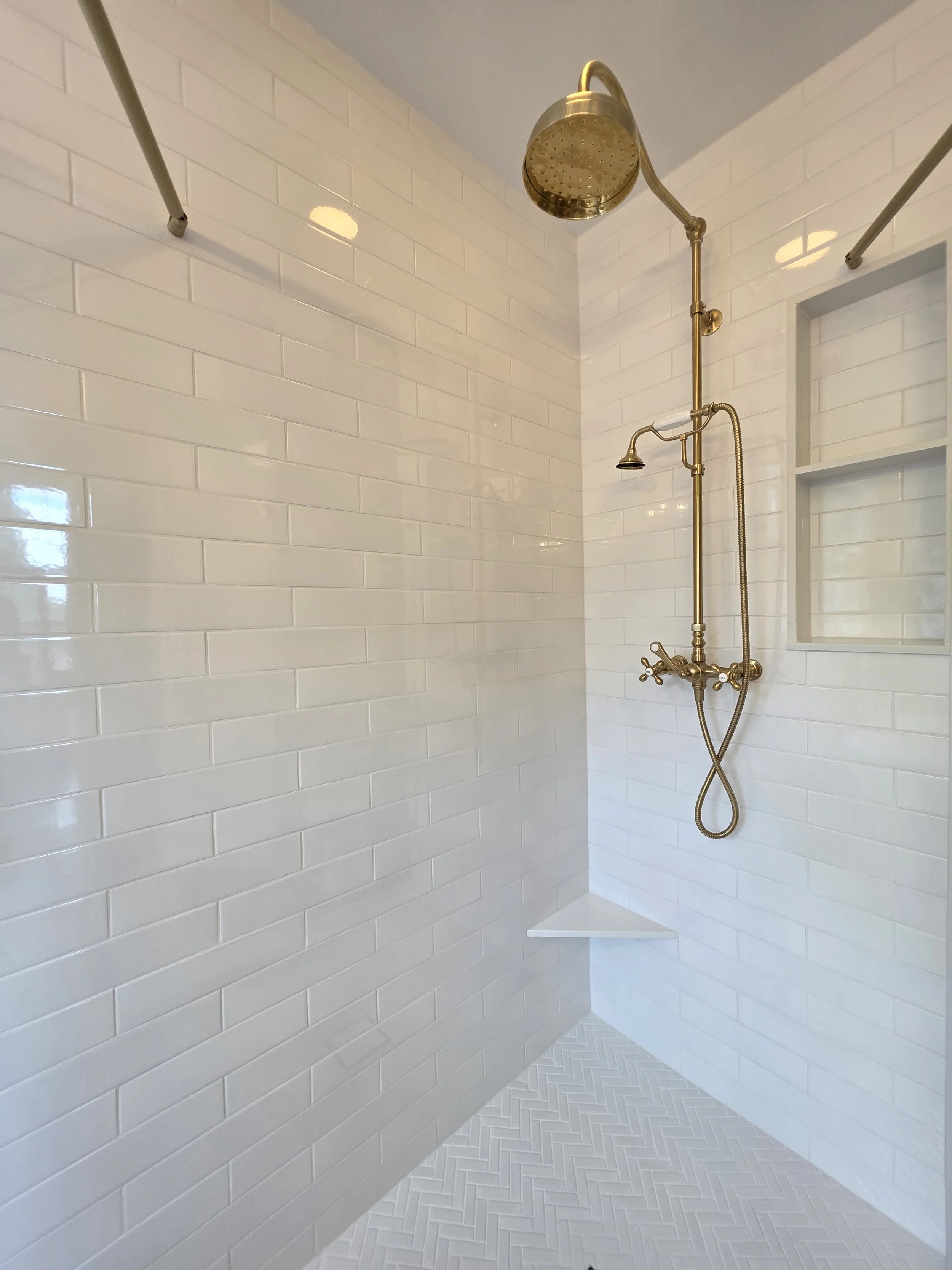 White subway shower tile and gold-toned fixtures.