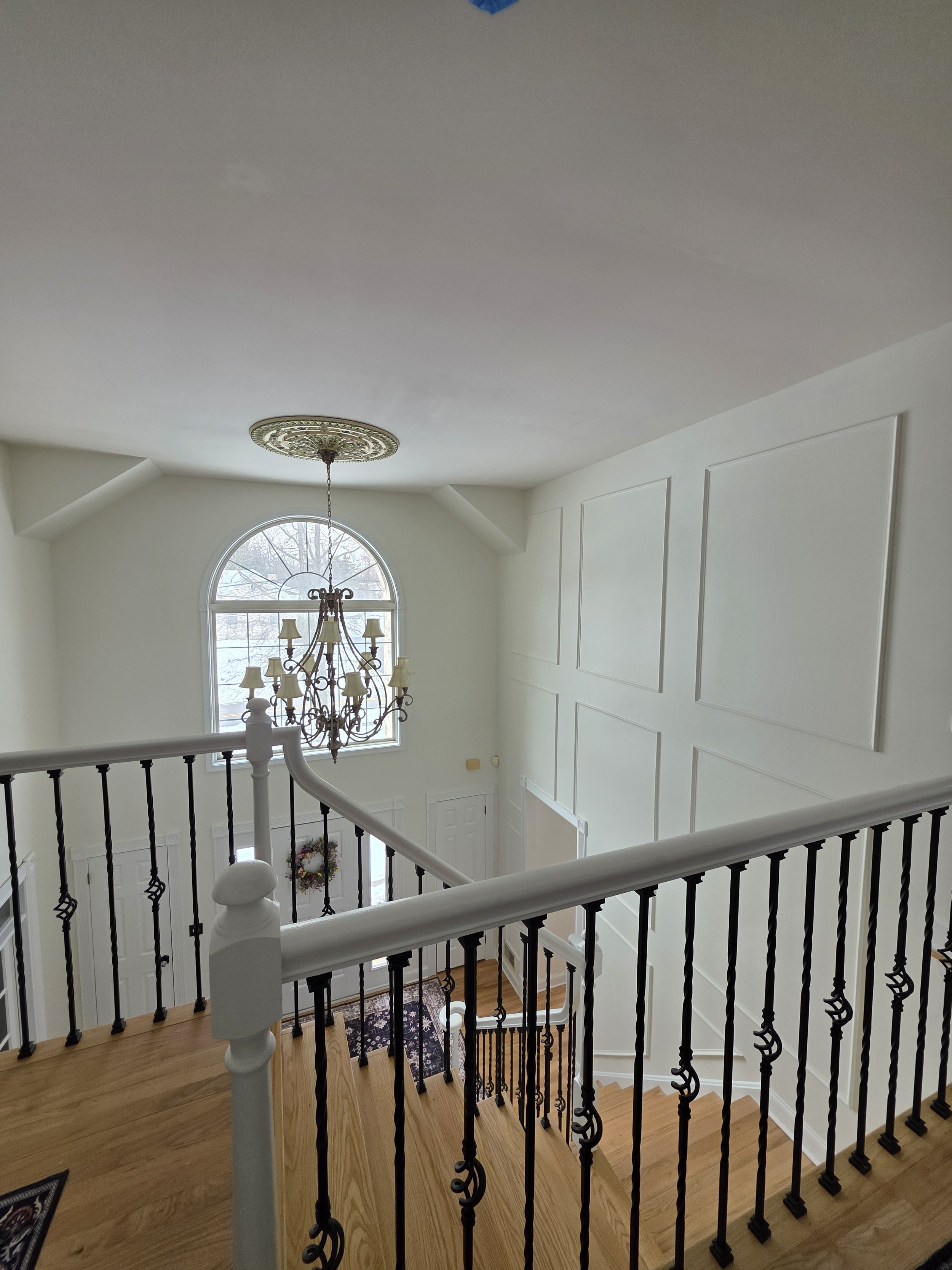 Upper landing with dark balusters, white rails and decorative wall trim overlooking the entryway.