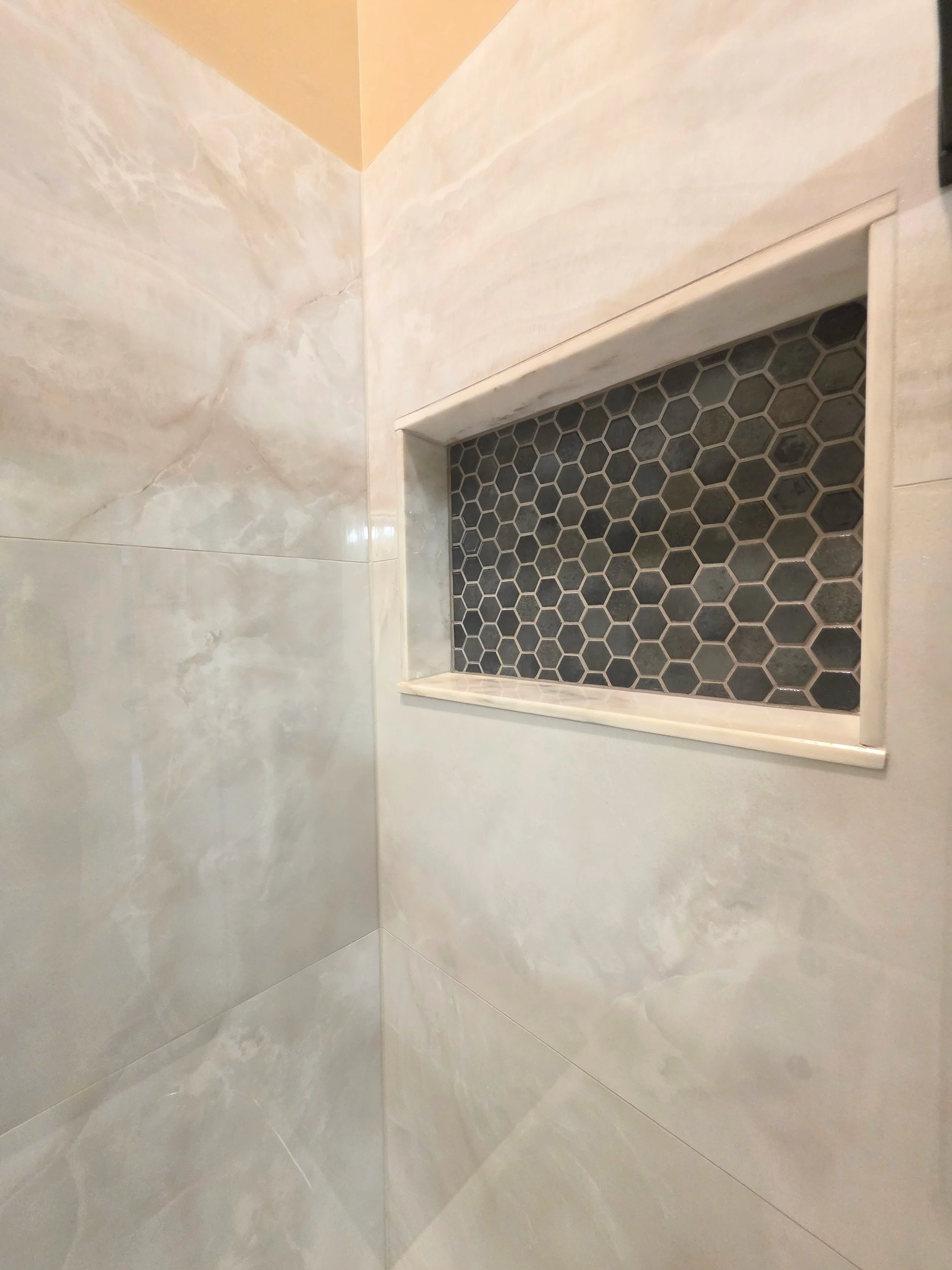 Close view of the white-trimmed niche with dark hexagonal accent tile.