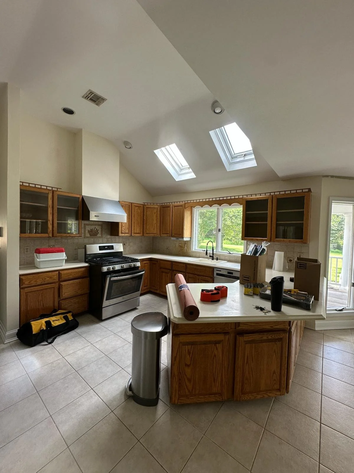 Before renovation: the original kitchen with wood cabinets, a smaller island and tiled floor.