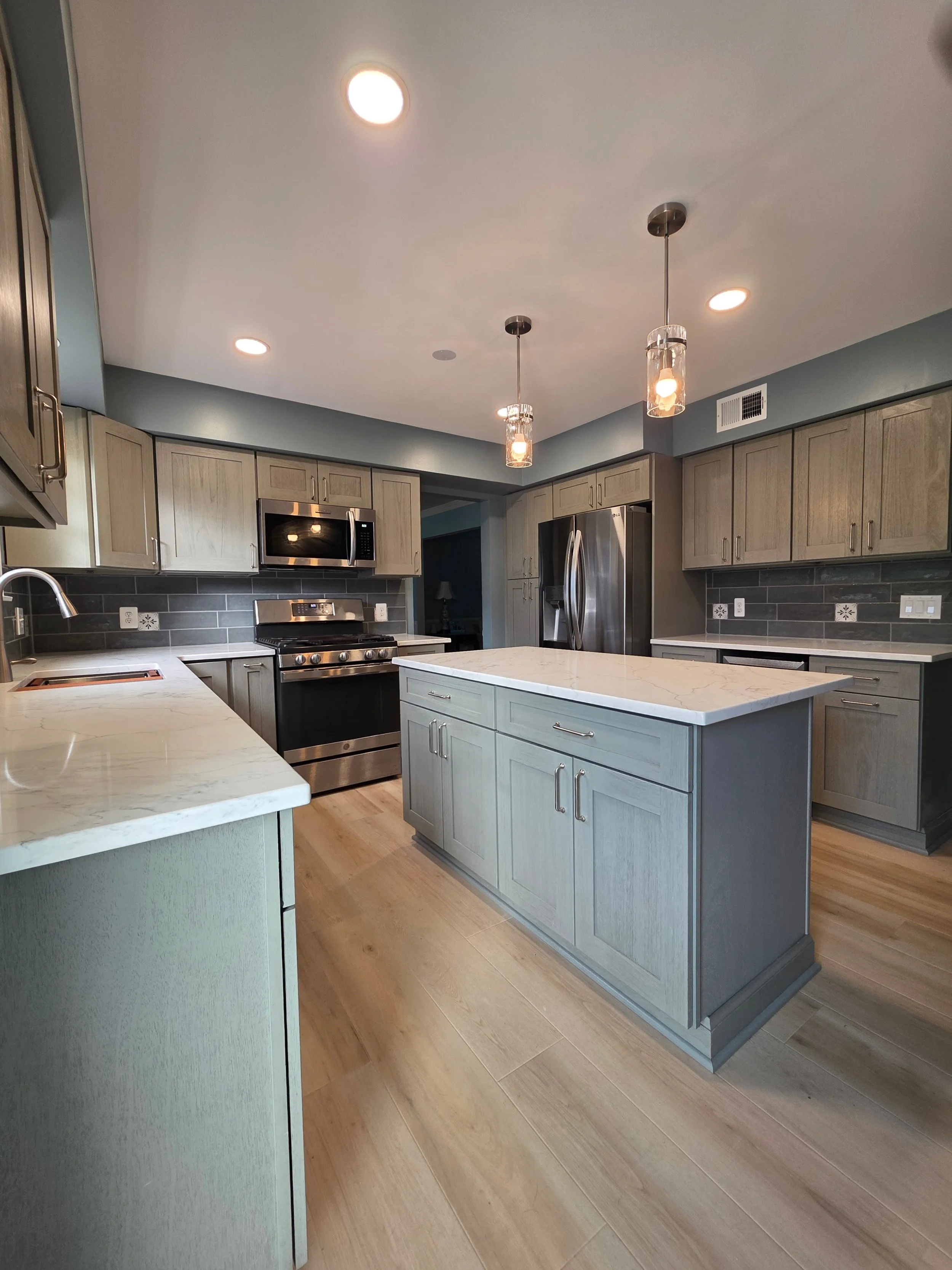 Gray kitchen island and cabinetry with pendant lighting.