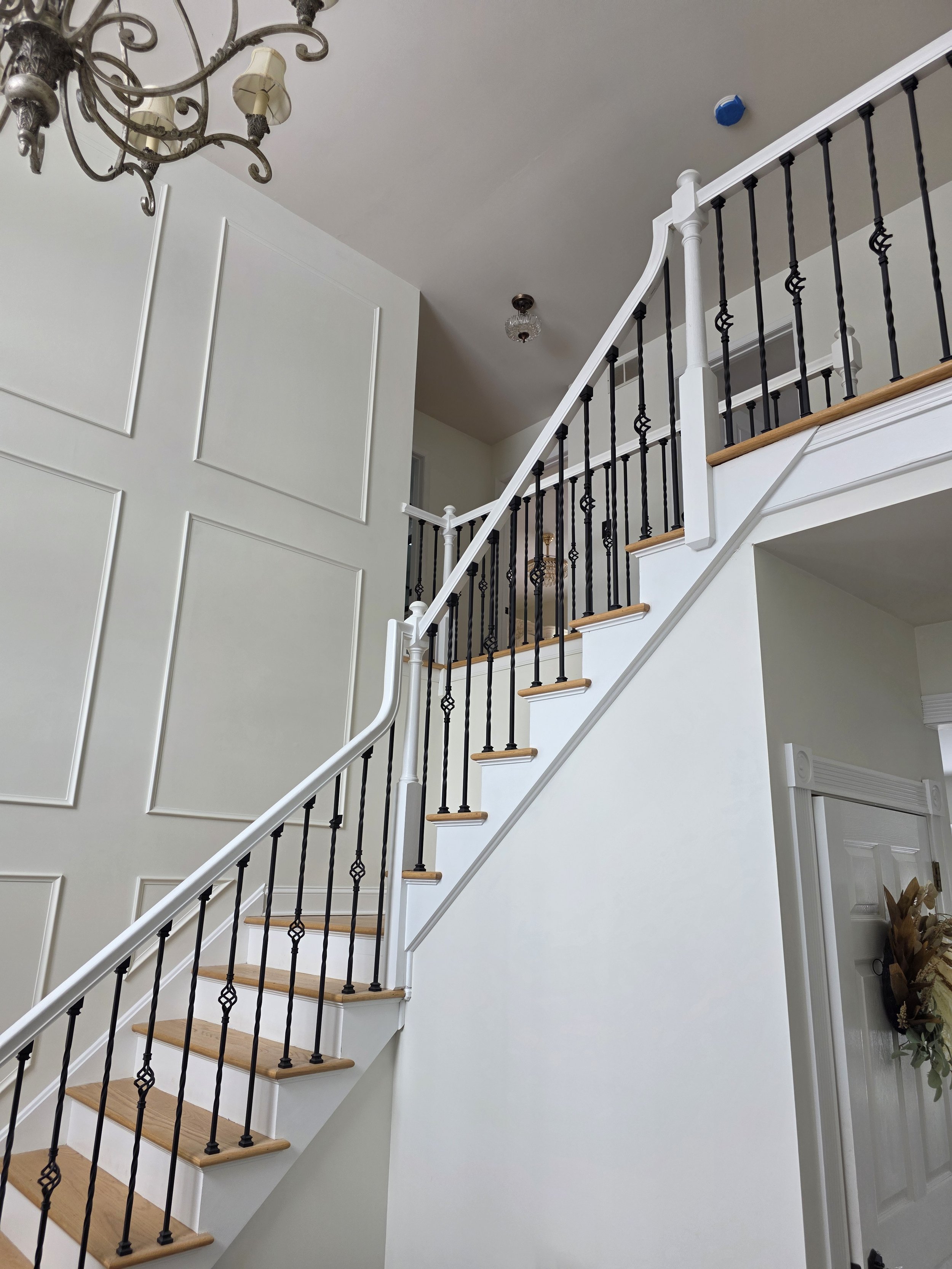Lucy and John’s remodeled staircase with white trim, wood treads and decorative dark balusters.