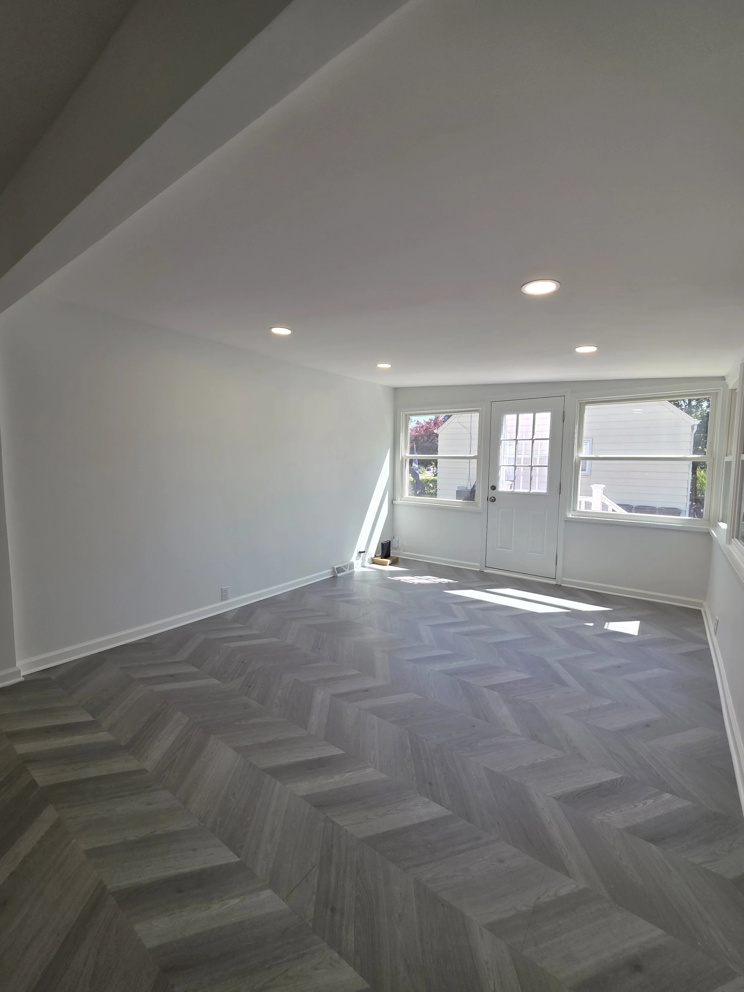 Wide view of the remodeled living area with recessed lights and continuous patterned flooring.