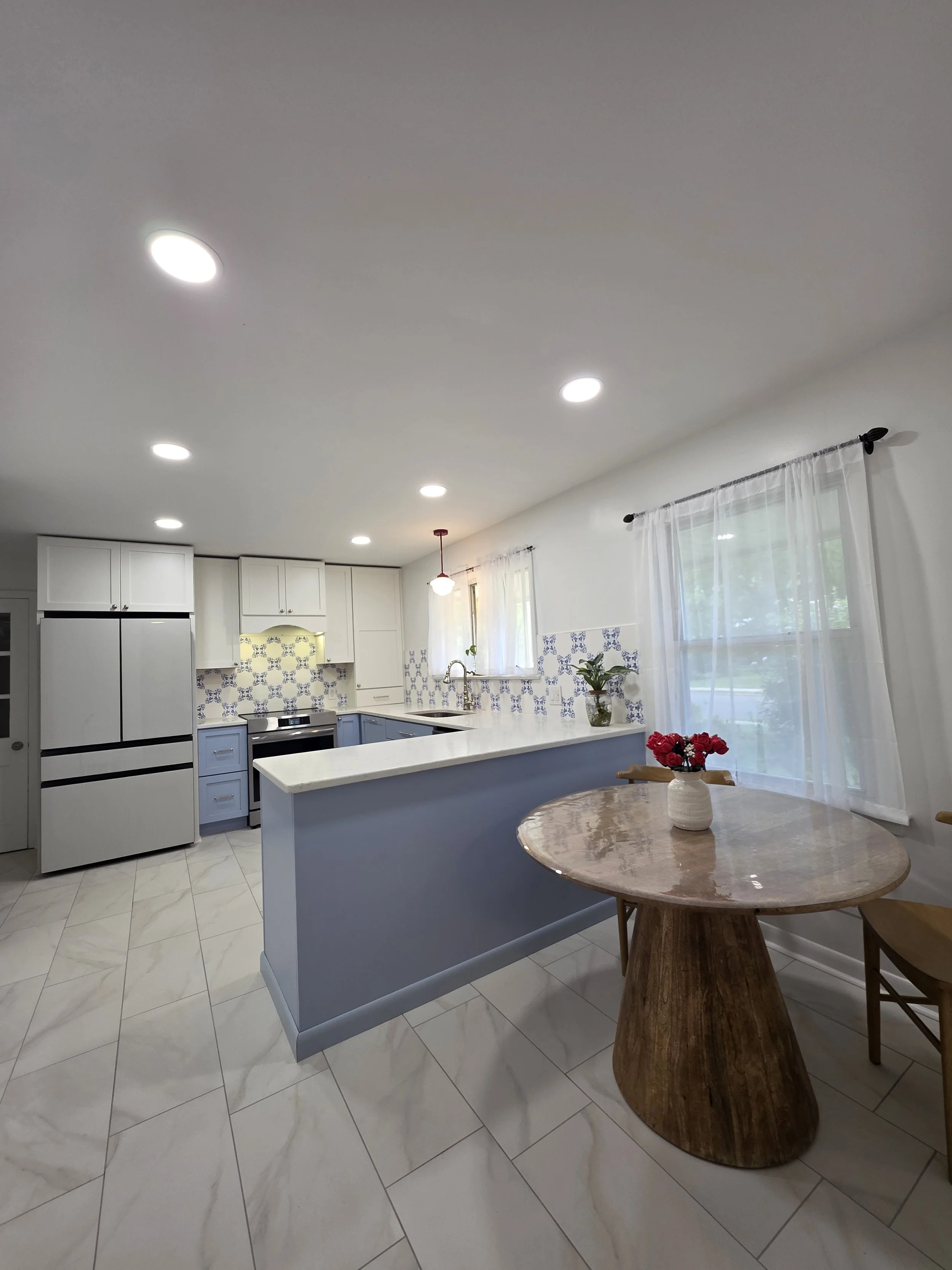 Kitchen peninsula and dining area beside bright windows.