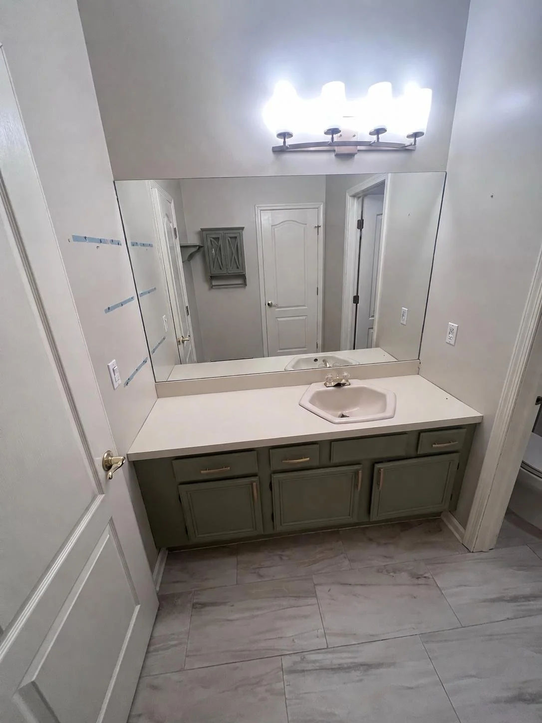 Before renovation: the original green vanity, white countertop and large wall mirror.