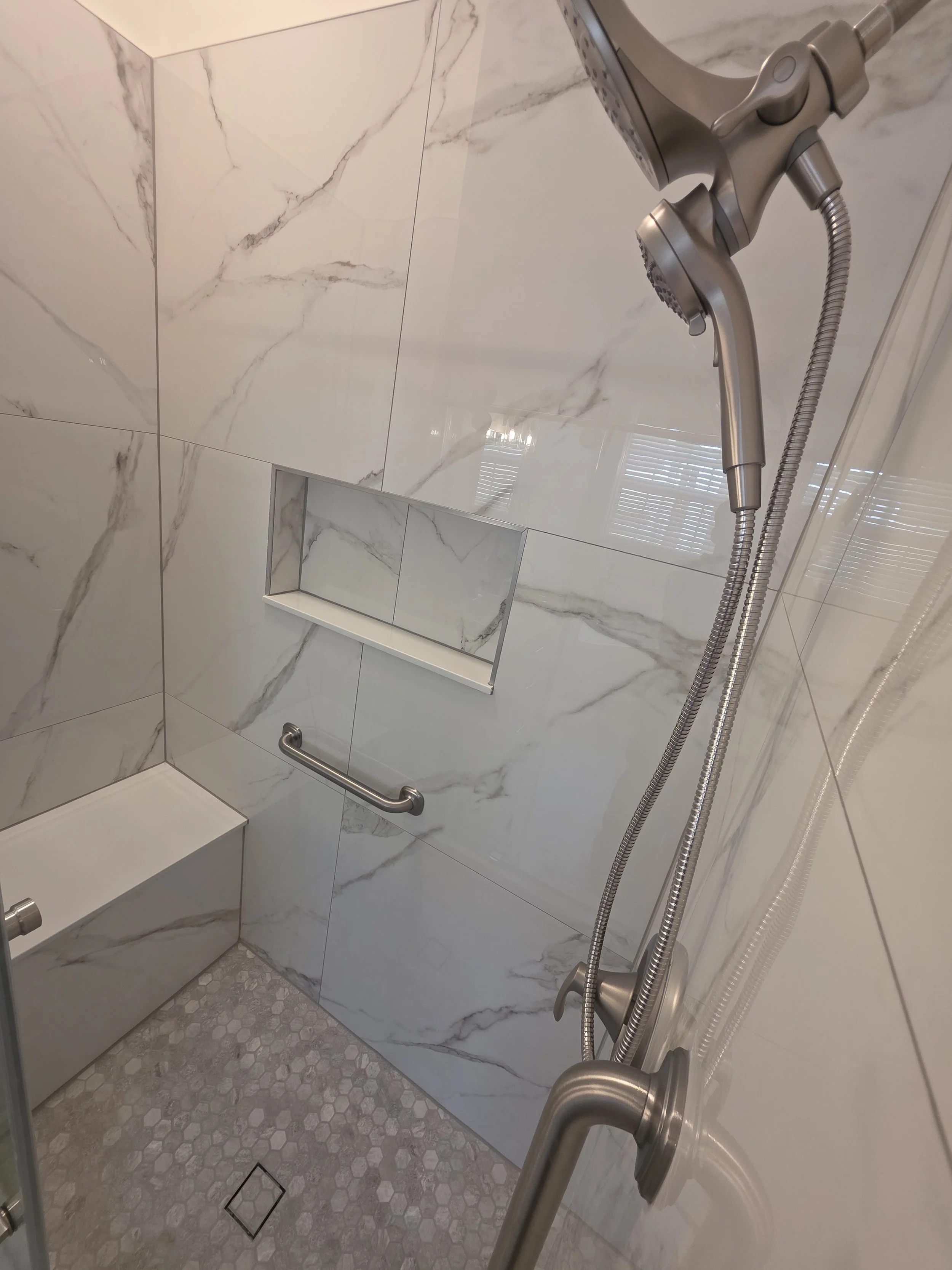 Marble-look shower tile, niche and handheld fixture.