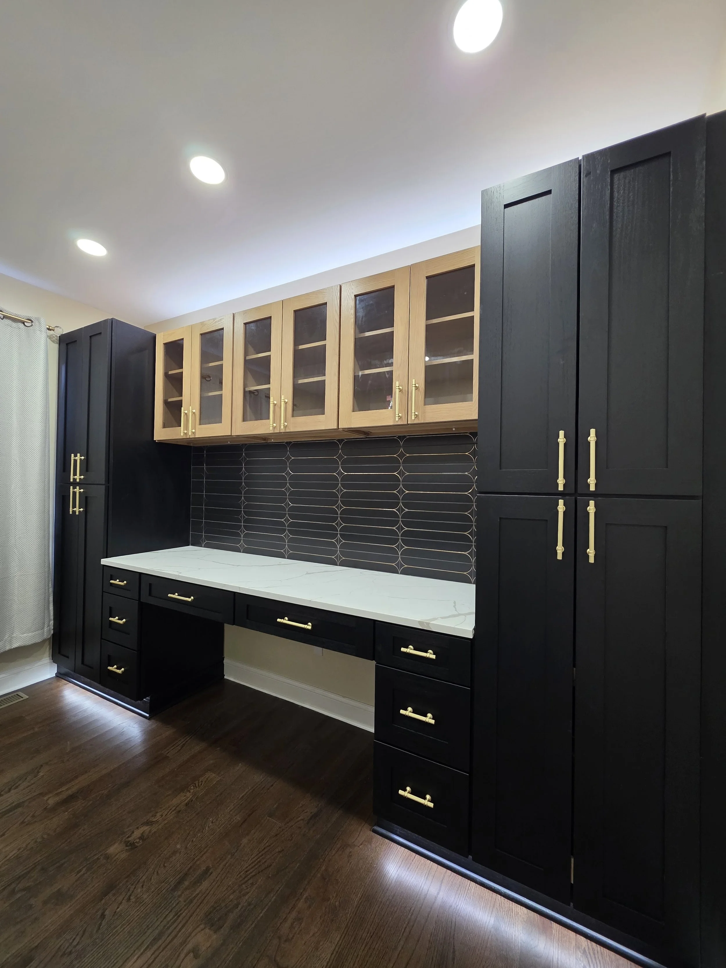 Office desk wall with light worktop and dark storage cabinets.