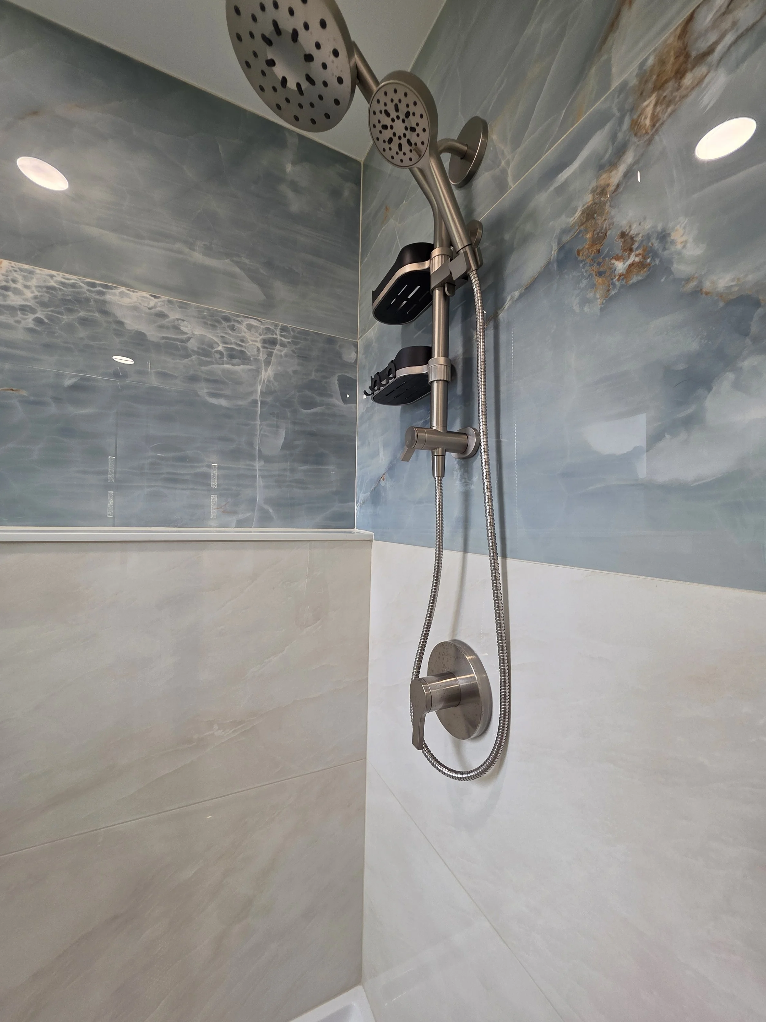 Beach-inspired shower tile with handheld fixture.