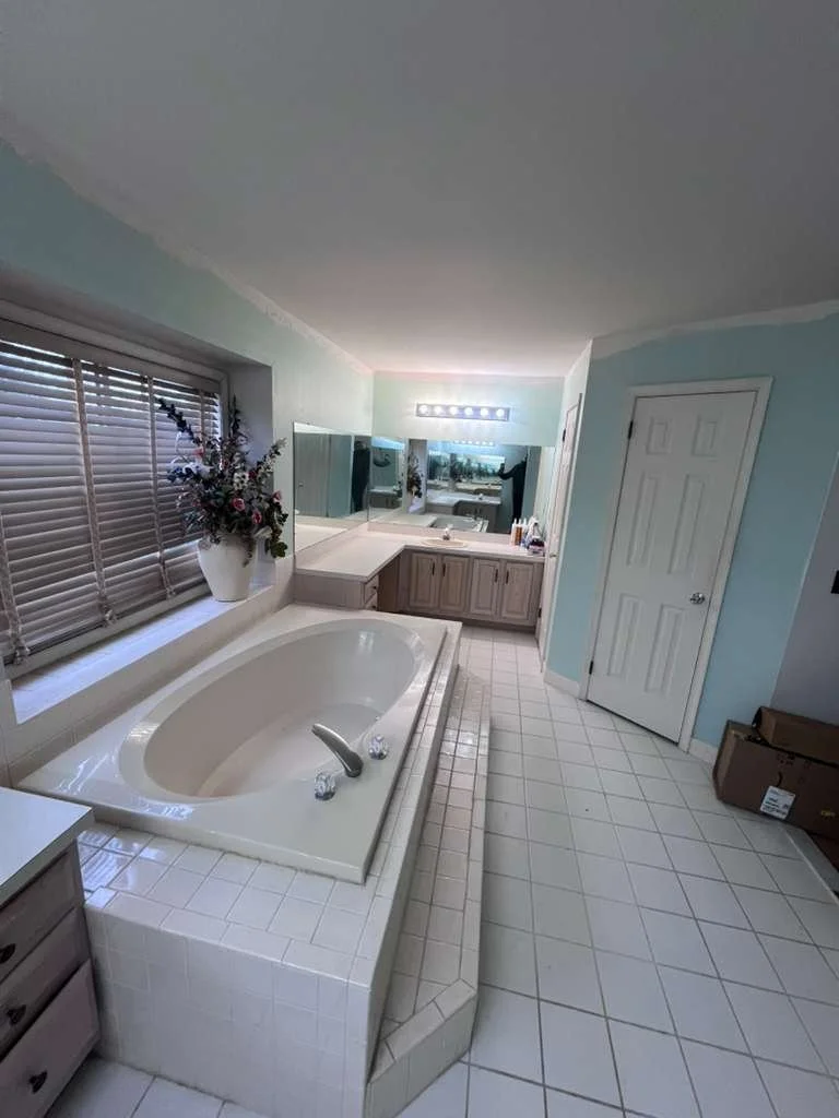 Before renovation: the original master bathroom with a built-in tub, square floor tile and vanity.