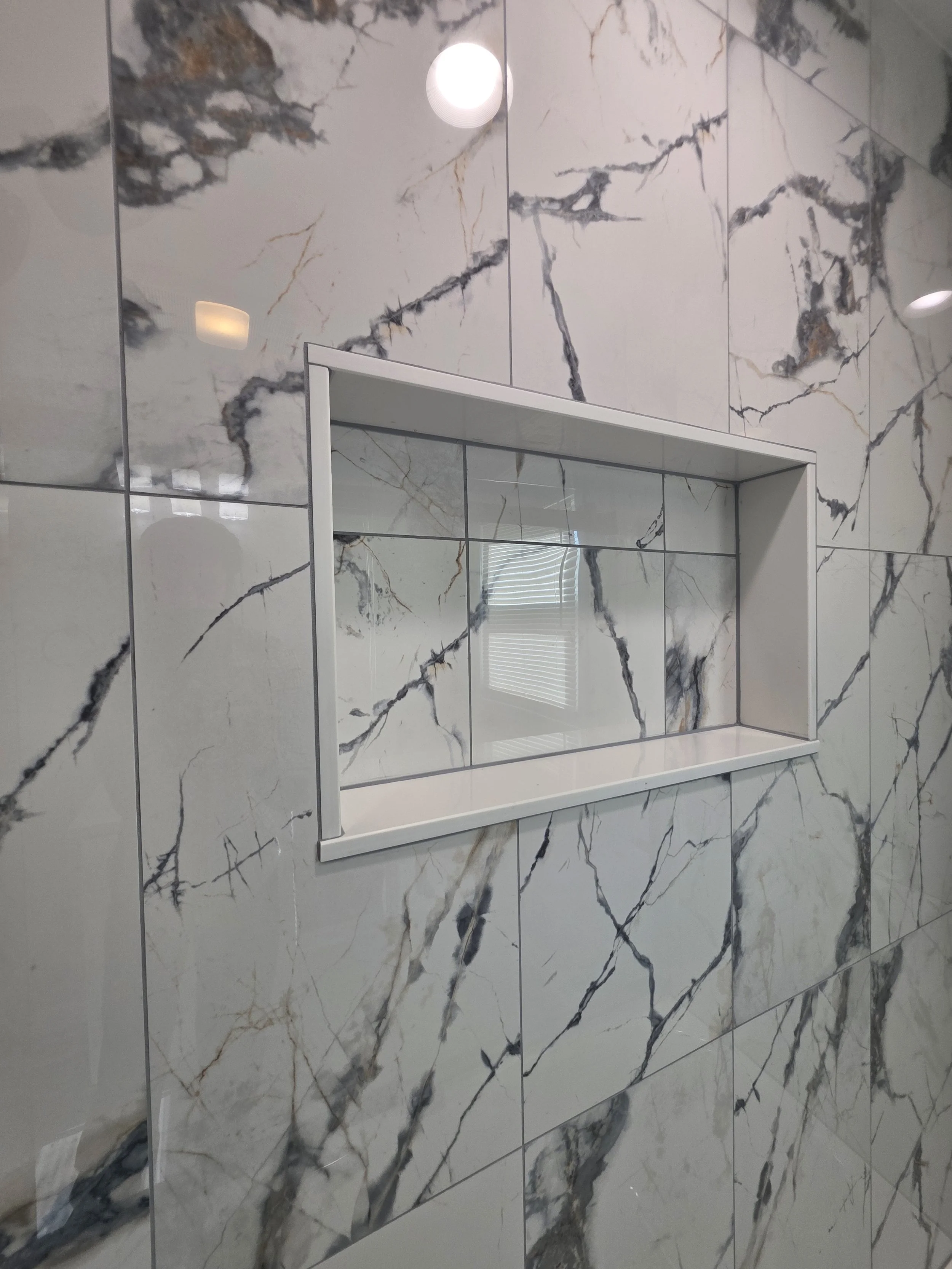 Close view of the white-trimmed niche set into the bold veined wall tile.