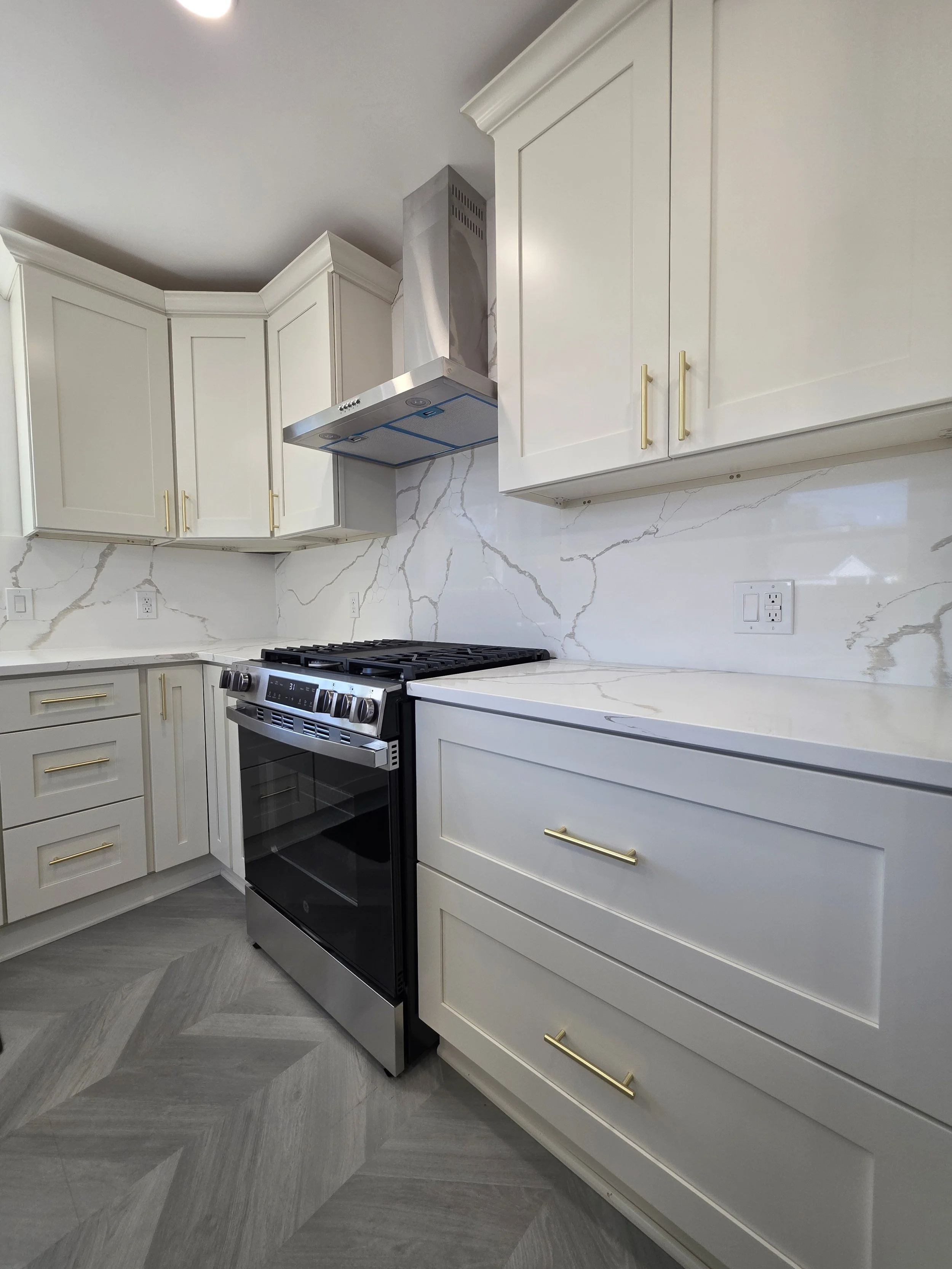 Range-side drawers with gold-tone hardware and continuous veined countertop and backsplash.
