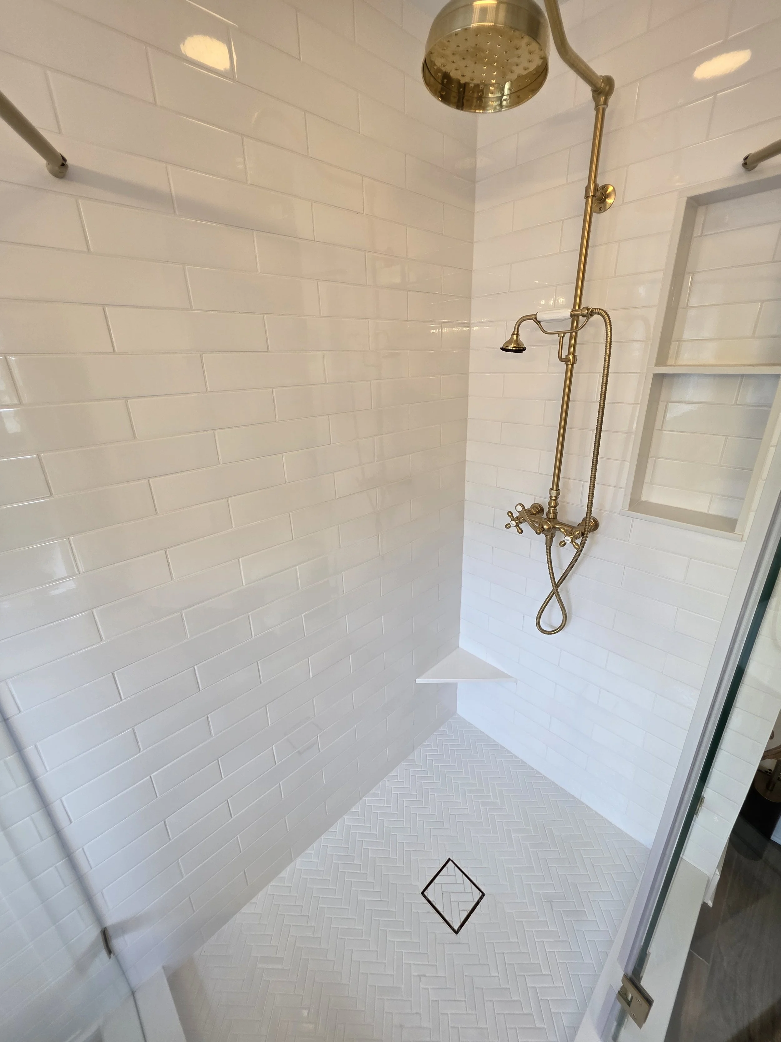 Shower floor and gold-toned handheld fixture.