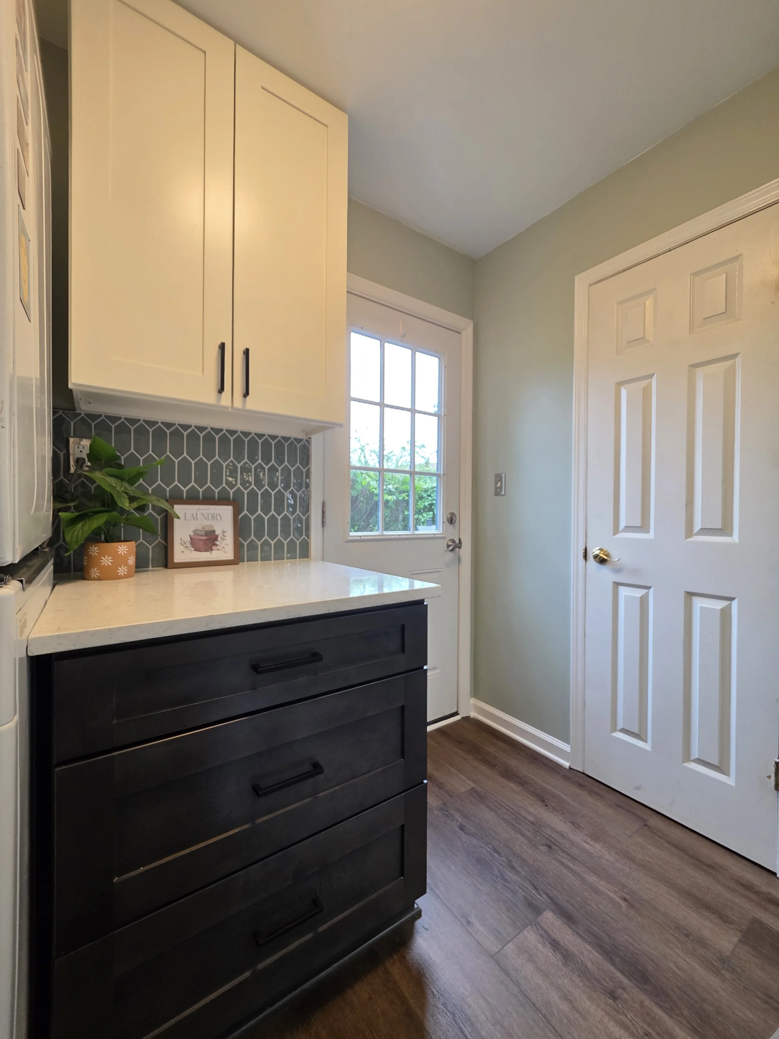 Laundry-room cabinetry with light upper cabinets, dark drawers and a patterned backsplash.