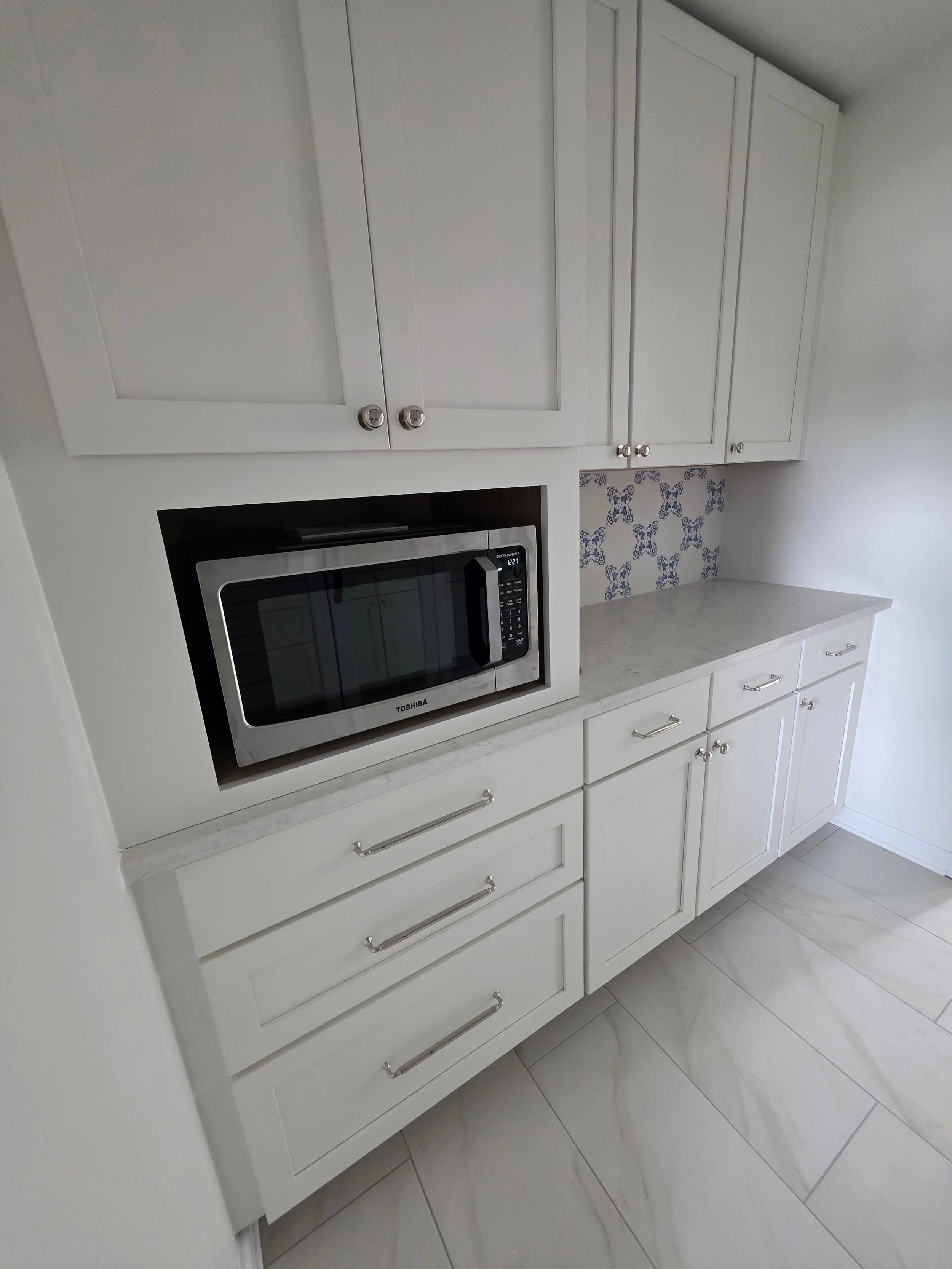 Bevin and TJ’s white pantry cabinets with built-in microwave and patterned backsplash.