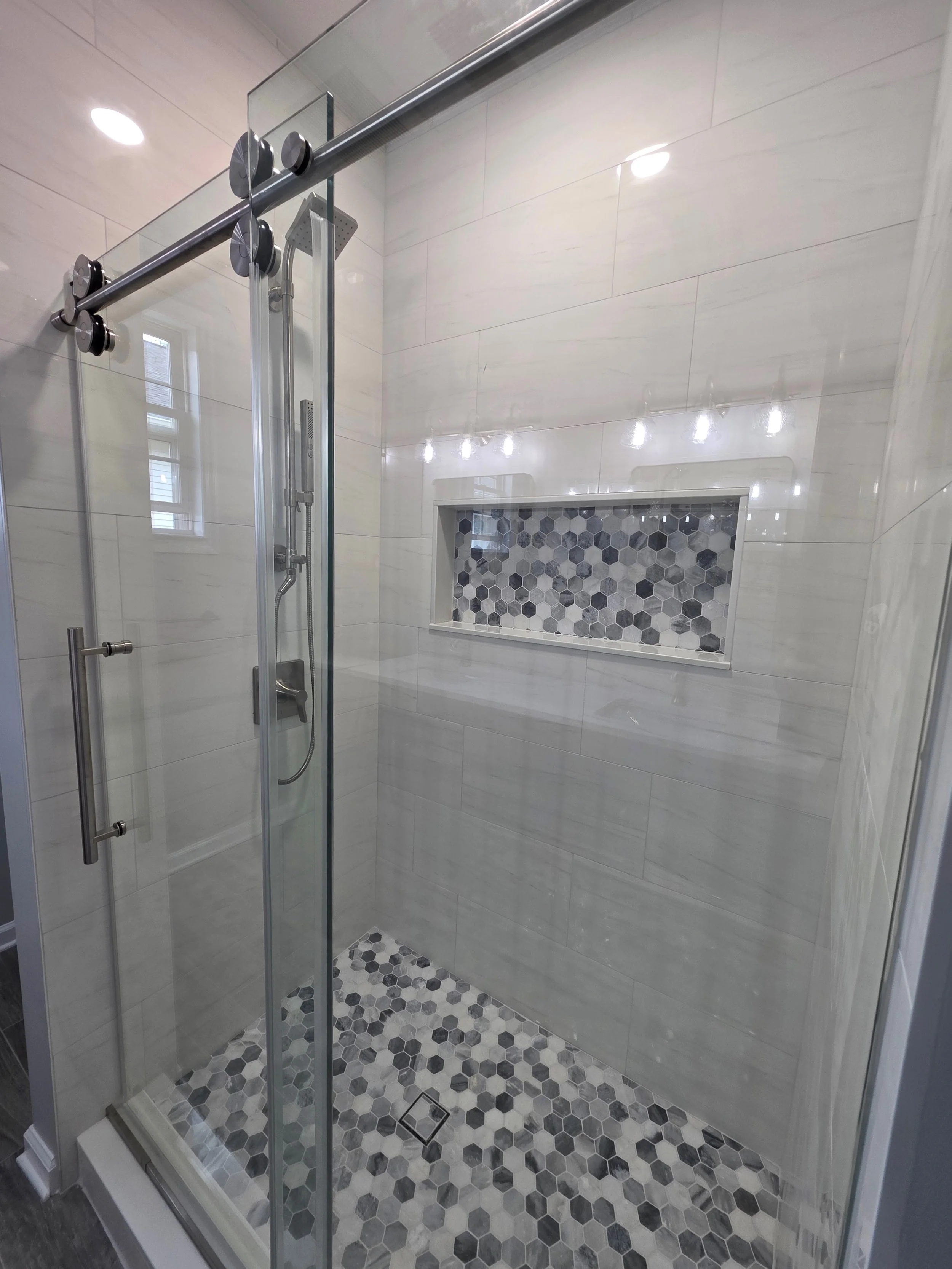 Sliding shower door and hexagonal mosaic accents.
