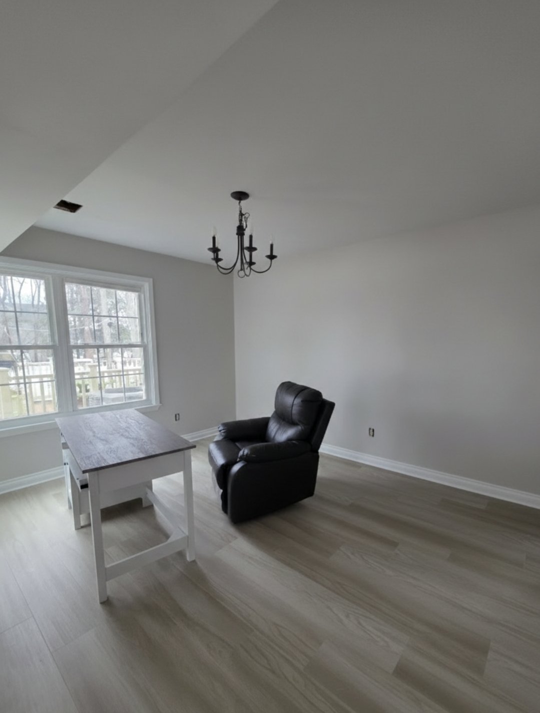 Dining nook with updated light flooring and fresh paint beneath a chandelier.