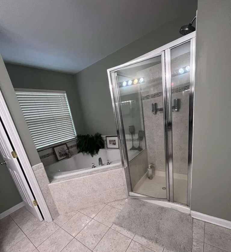 Before renovation: the original built-in bathtub and separate framed shower enclosure.
