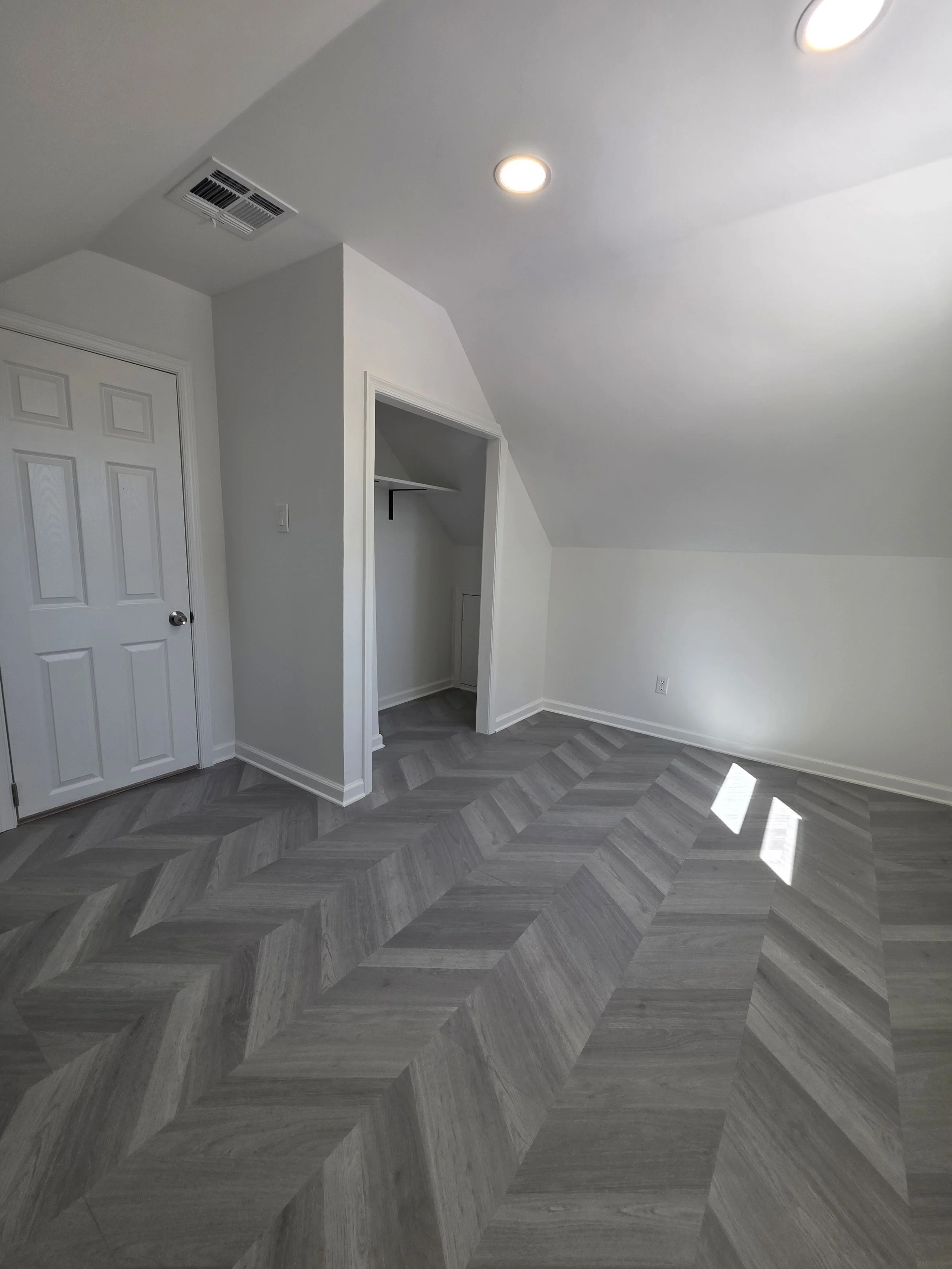 Upstairs room with pale walls, white doors and continuous patterned flooring.