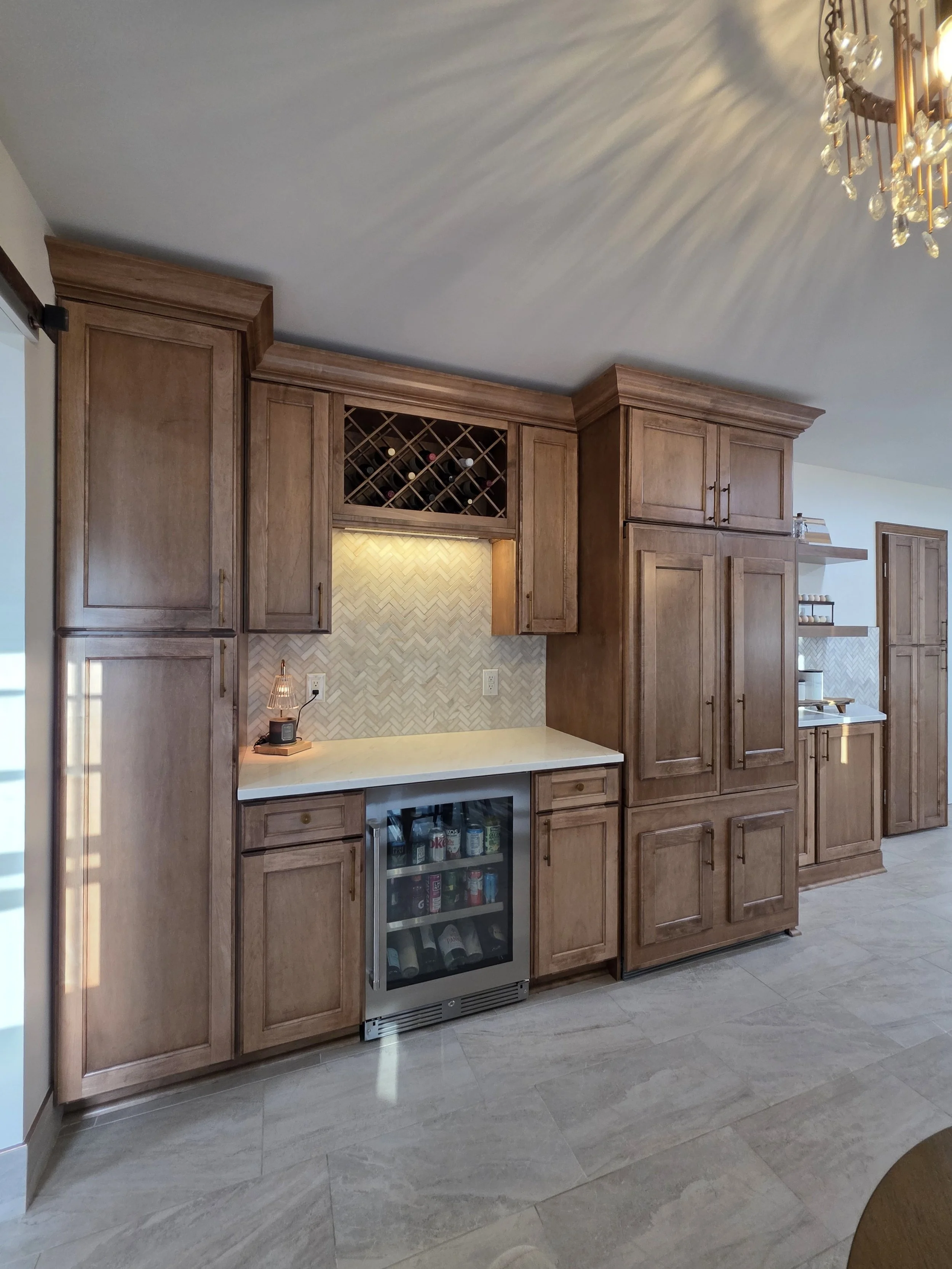 Built-in beverage refrigerator, wine rack and tall wood storage cabinets.