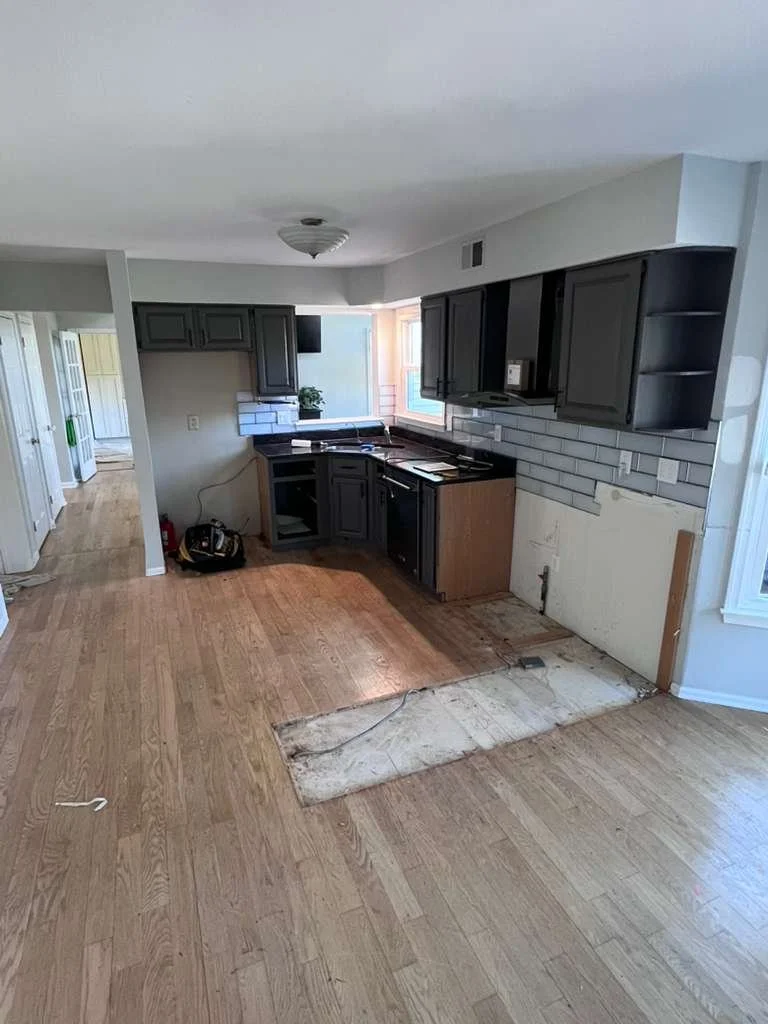 Before renovation: the original kitchen with dark cabinetry and unfinished wall areas.