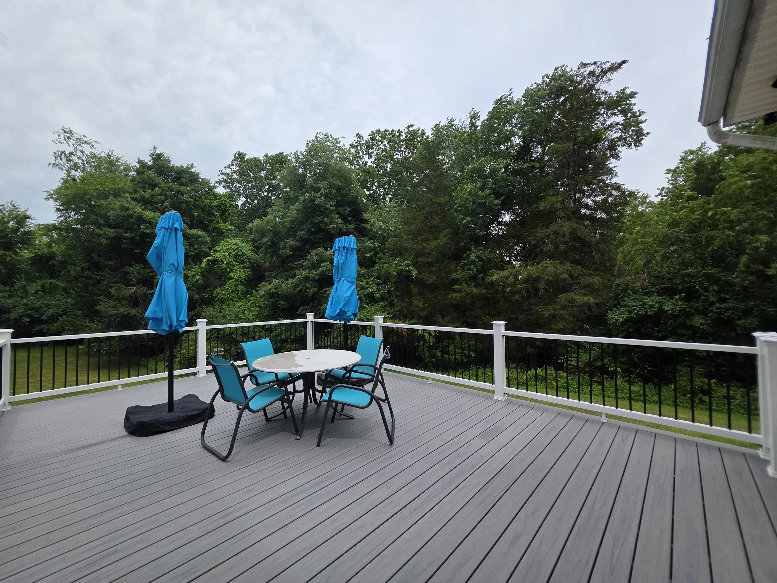 Wide view of the finished gray deck with white perimeter railings and black balusters.