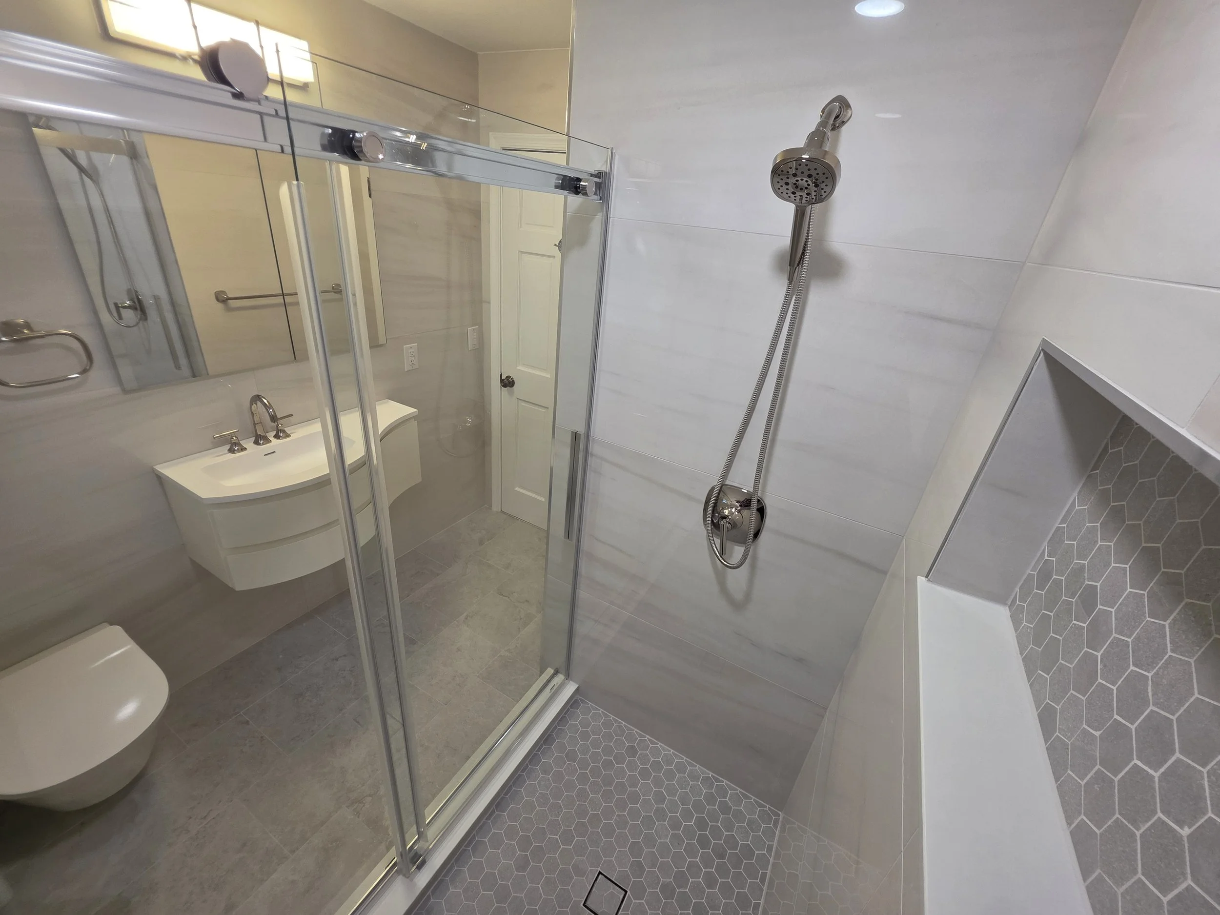 Shower interior with handheld fixture and niche.